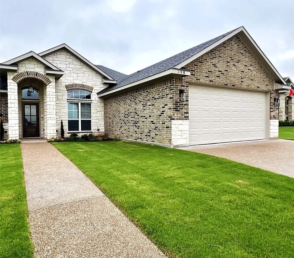 Stone and brick exterior featuring a covered entry with an arched architectural detail