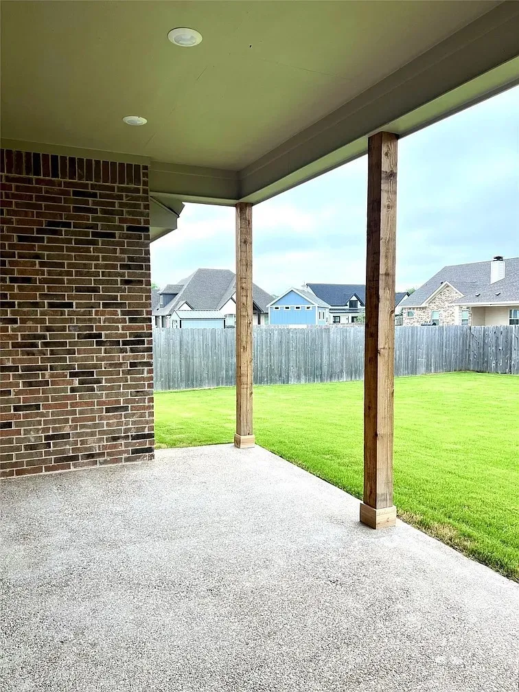 Covered patio with a textured concrete surface, supported by two wooden posts