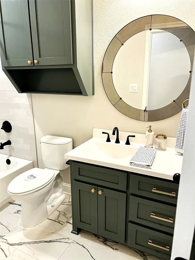 Bathroom featuring a dark green vanity with brass hardware, a white undermount sink, and a white countertop
