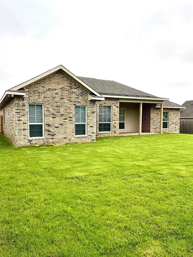 Brick veneer exterior with a covered patio and expansive green lawn