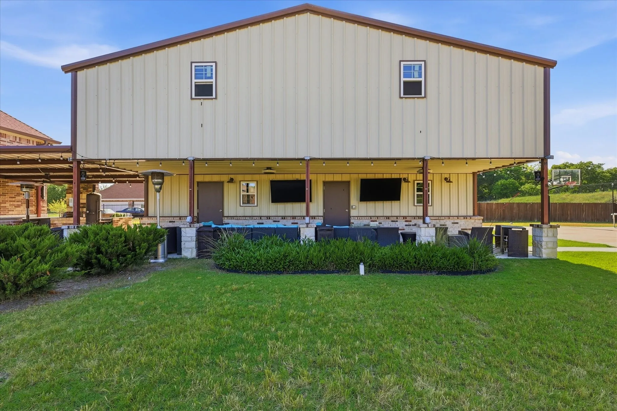 Rear exterior featuring a covered patio, two entry doors, and overhead string lighting