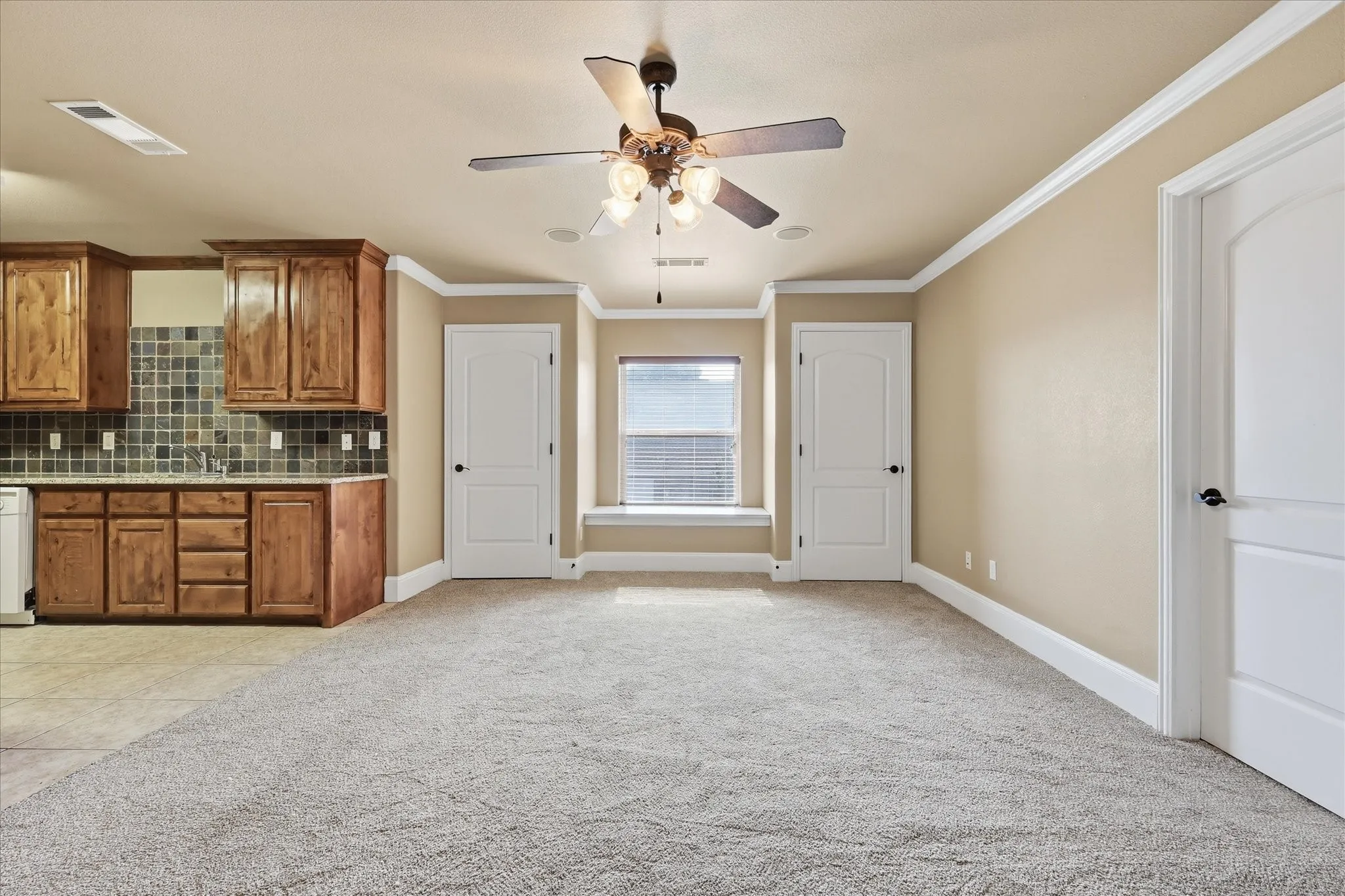 Open-concept room featuring a built-in kitchenette with wood cabinetry and tile backsplash