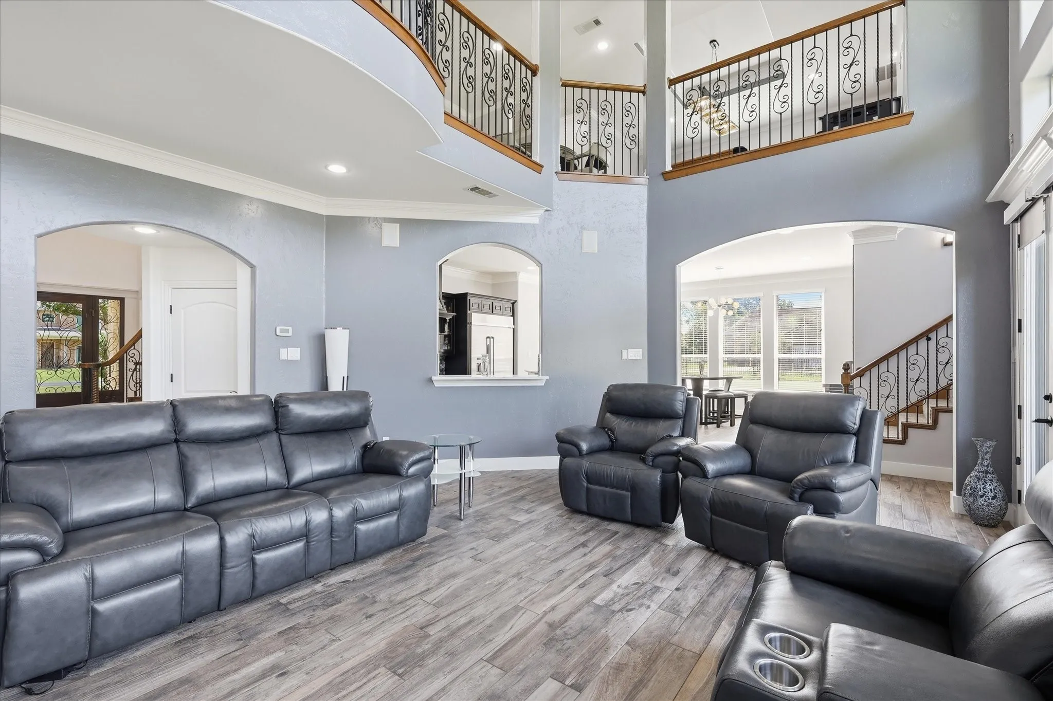 Two-story living area featuring vaulted ceilings, wood-finish flooring, and arched doorways