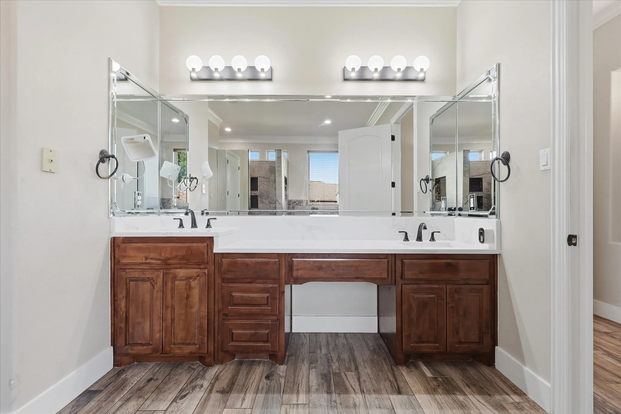 Double vanity with wood-finish cabinetry, white countertops, dual undermount sinks, and matte black fixtures