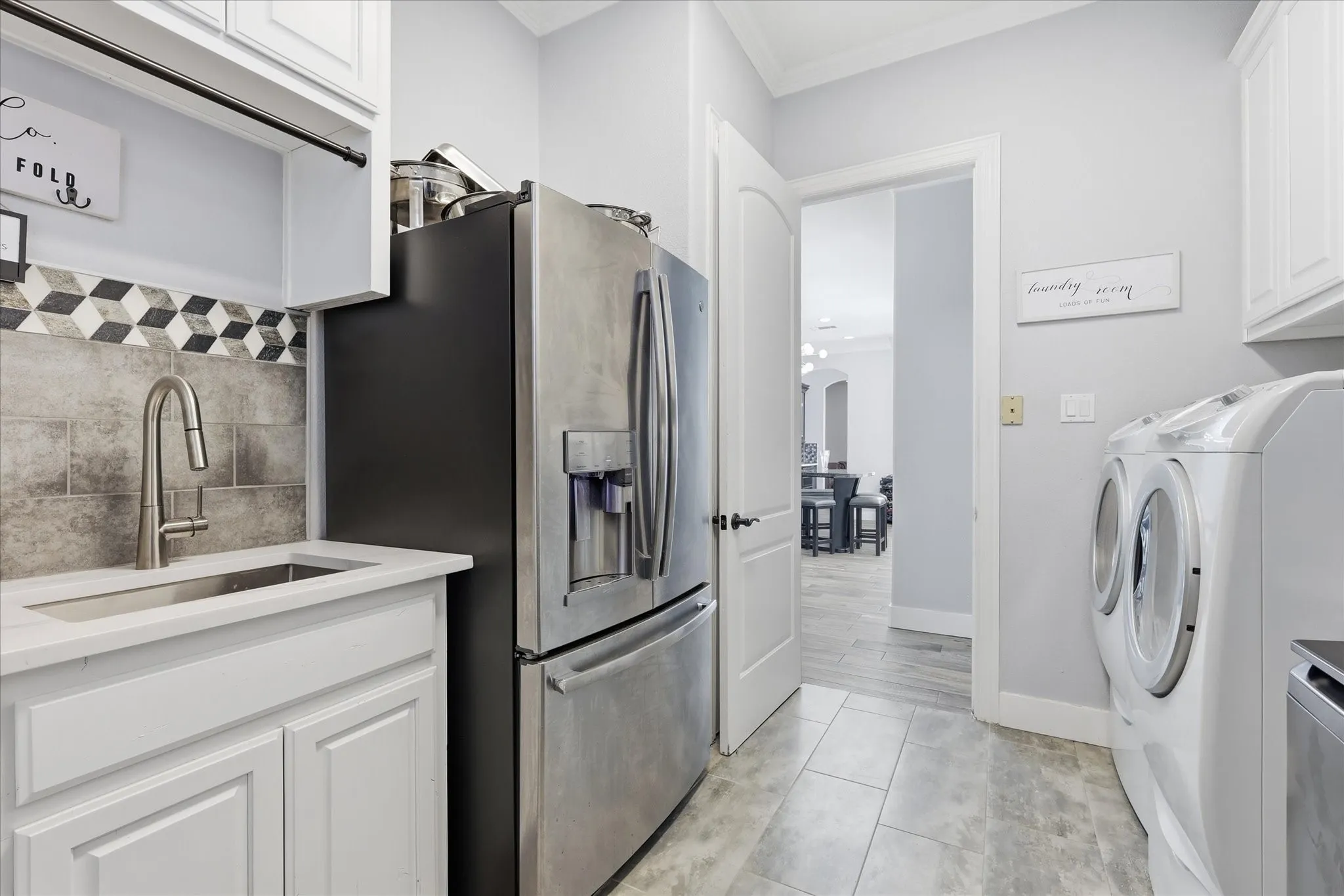 Utility room featuring a built-in sink with a gooseneck faucet, white cabinetry, and tile flooring