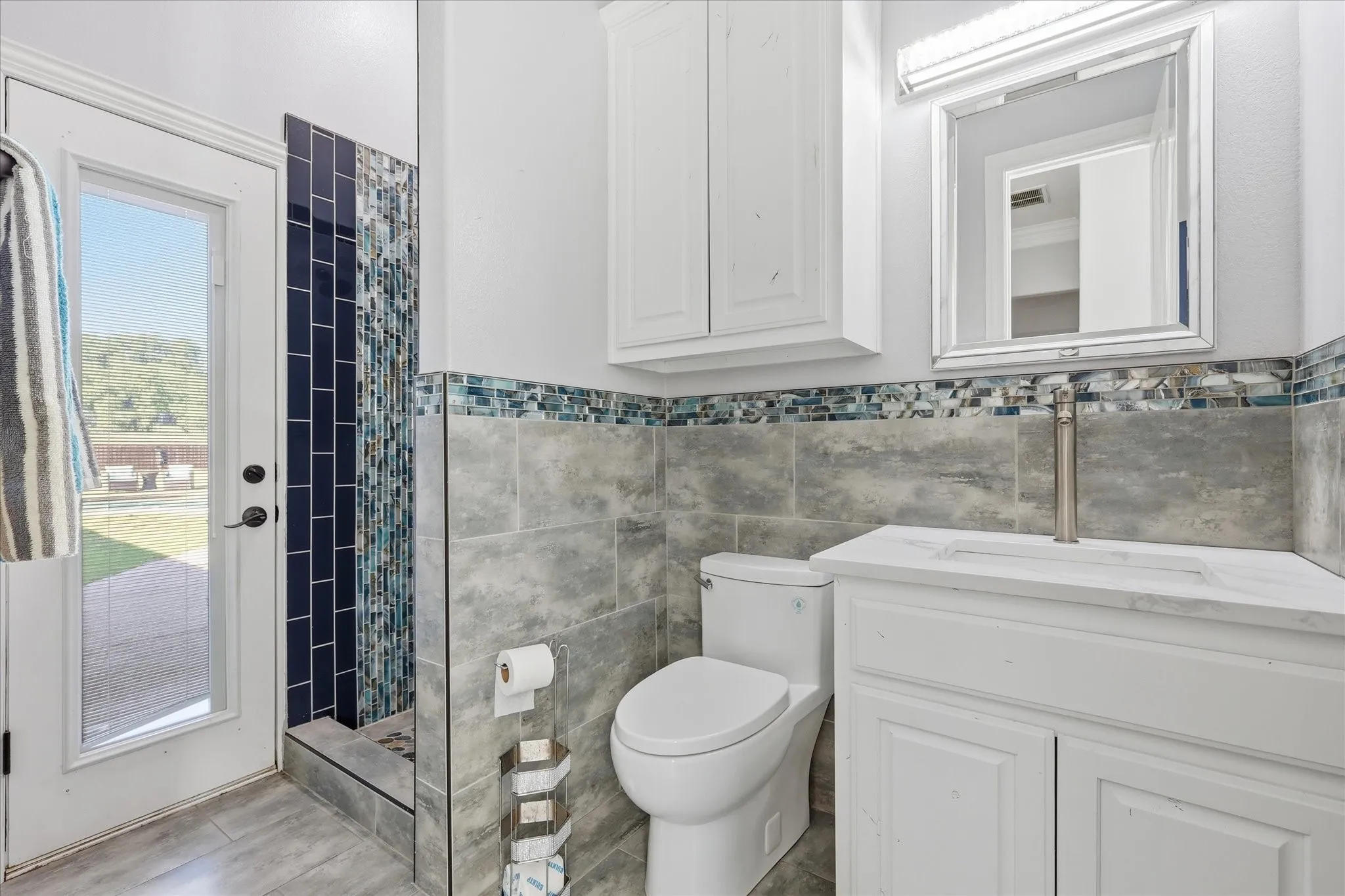 Bathroom featuring a white vanity with integrated sink, white storage cabinetry, and a framed mirror with overhead lighting