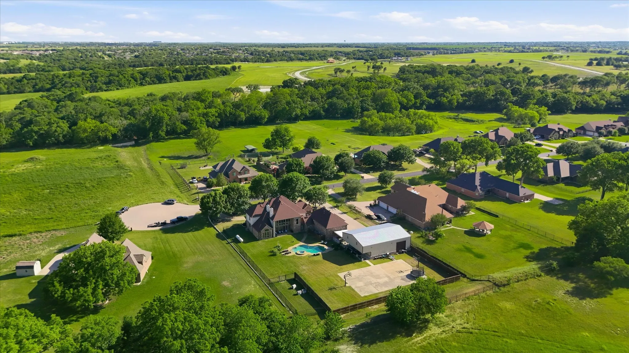 Expansive property featuring a private swimming pool, detached accessory building, paved sports court, and an open-air gazebo