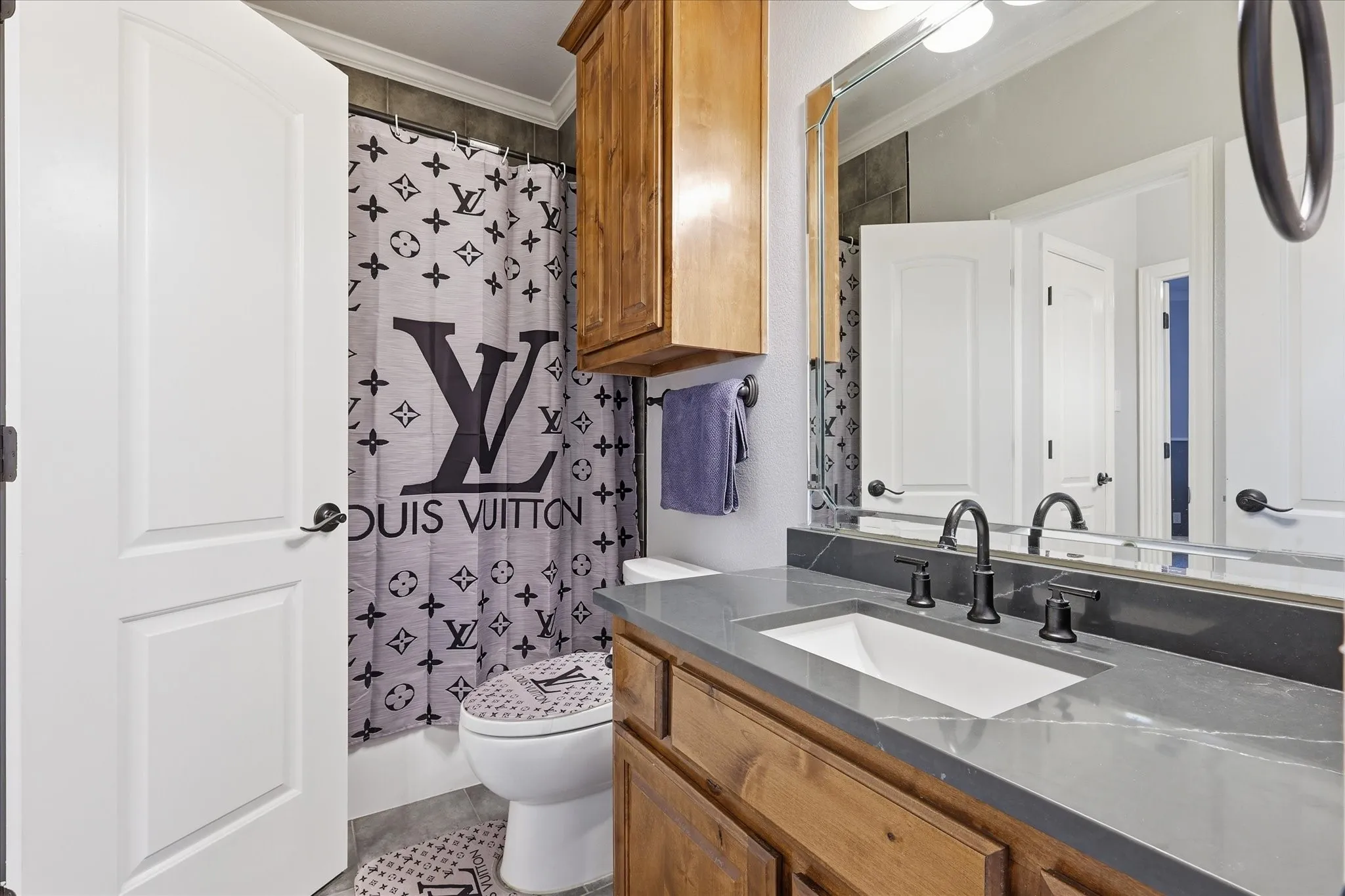 Bathroom featuring a wood vanity with a gray countertop, an undermount sink, and a matte black faucet
