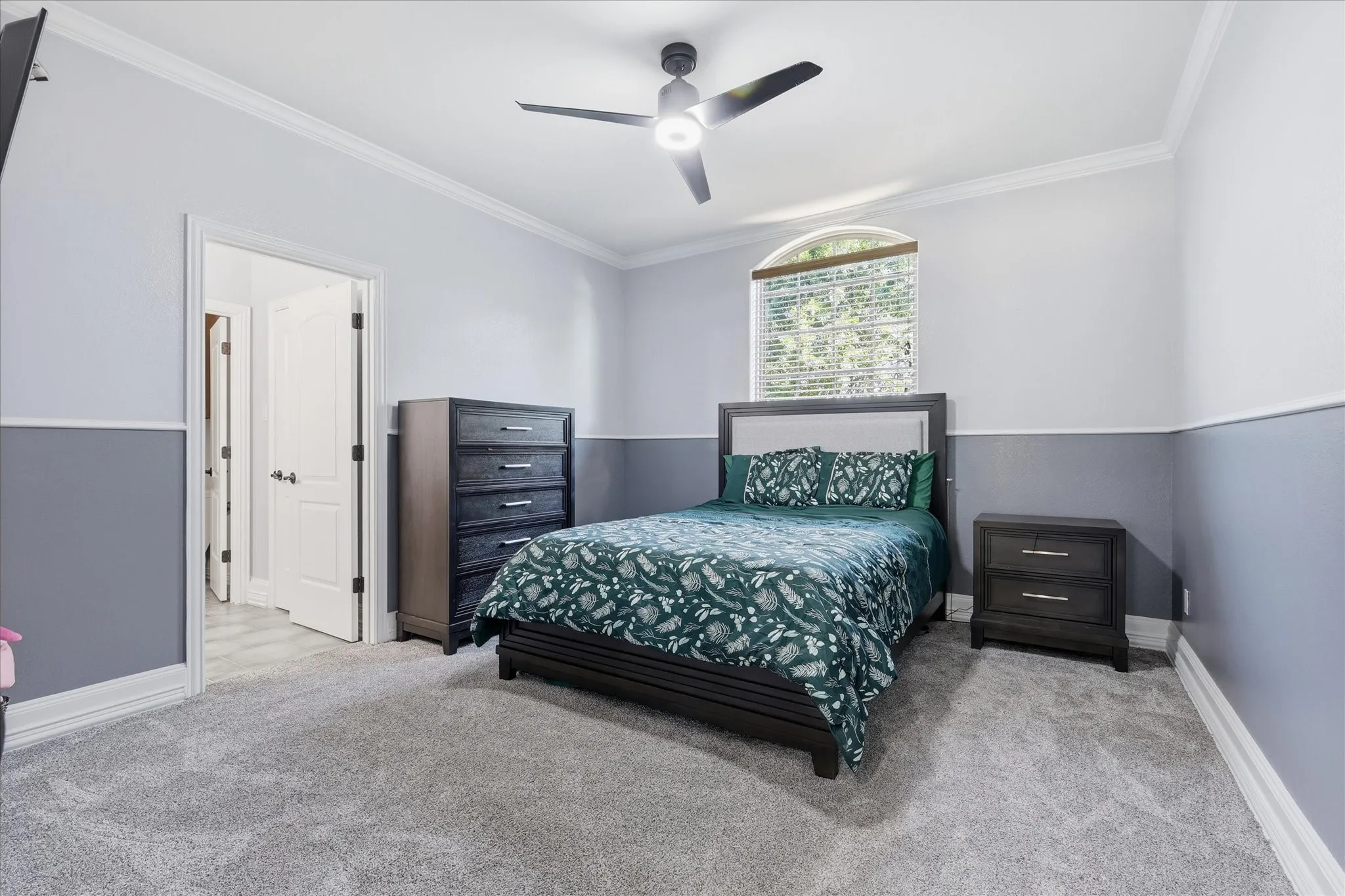 Room featuring light gray carpet, two-tone walls with a chair rail, and crown molding