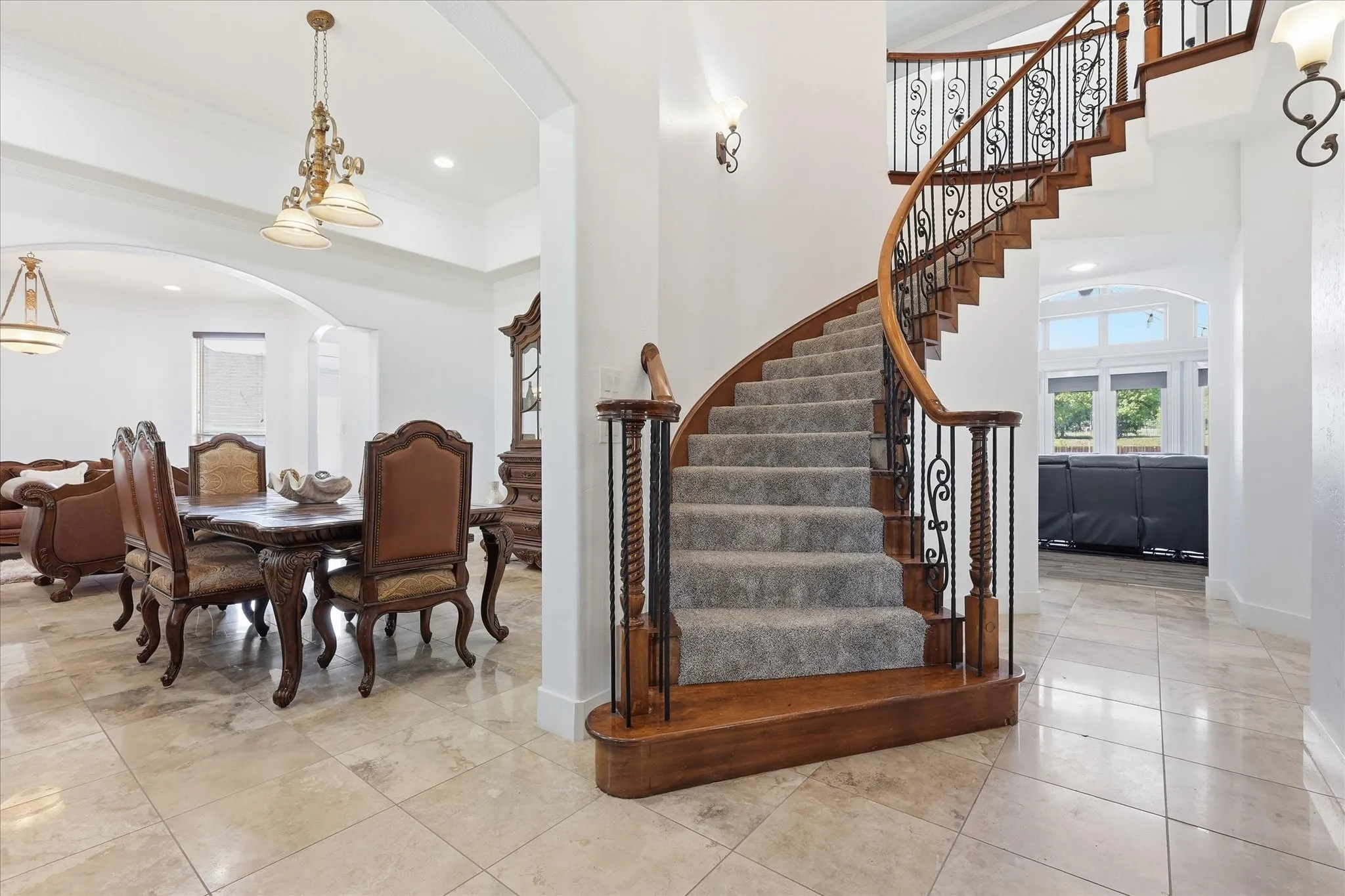 Curved staircase featuring wood-finish treads and risers, wrought iron balusters, and a wood-finish handrail