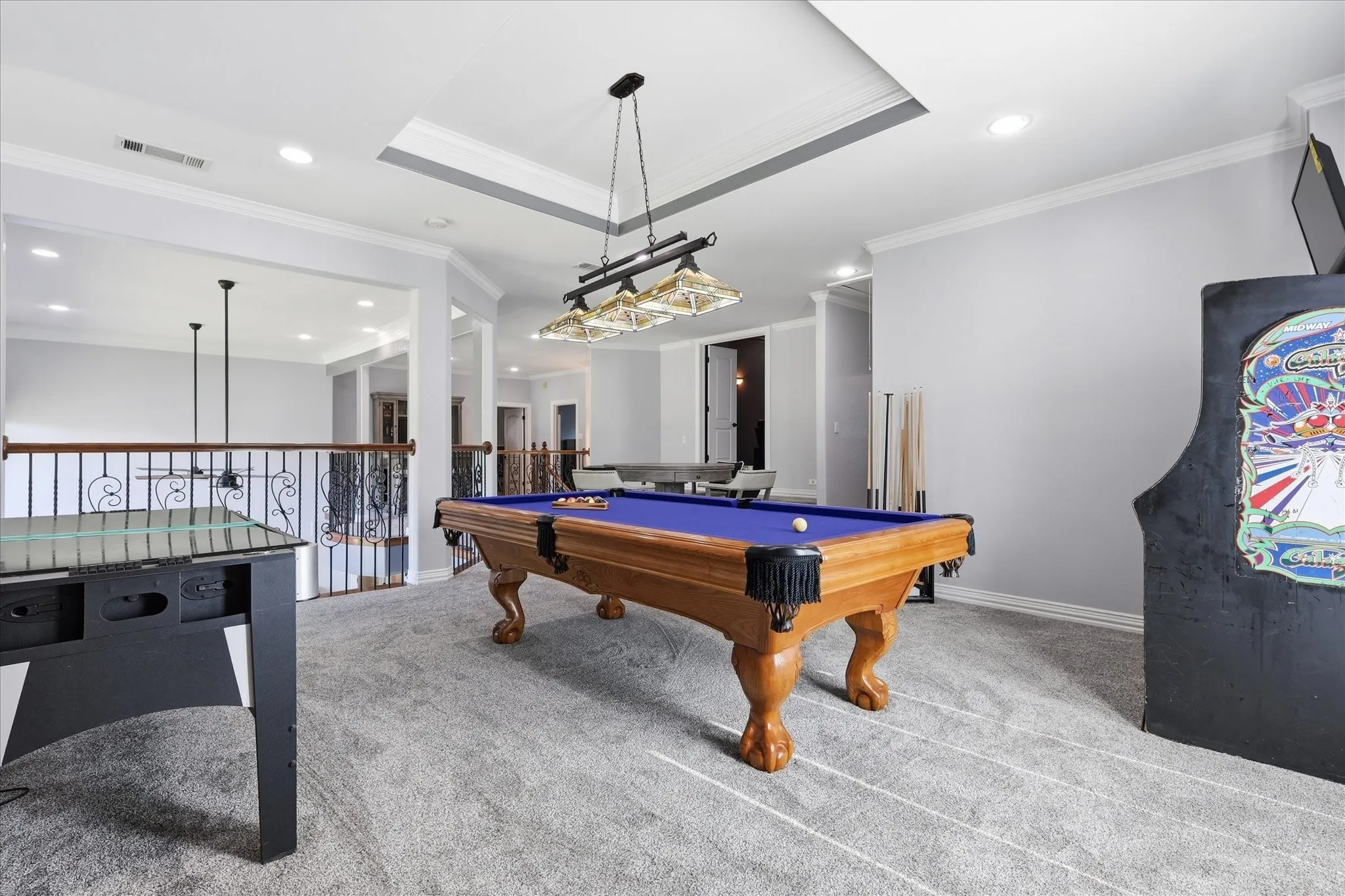 Upper-level lounge area featuring light gray carpeting, recessed lighting, and a tray ceiling with crown molding