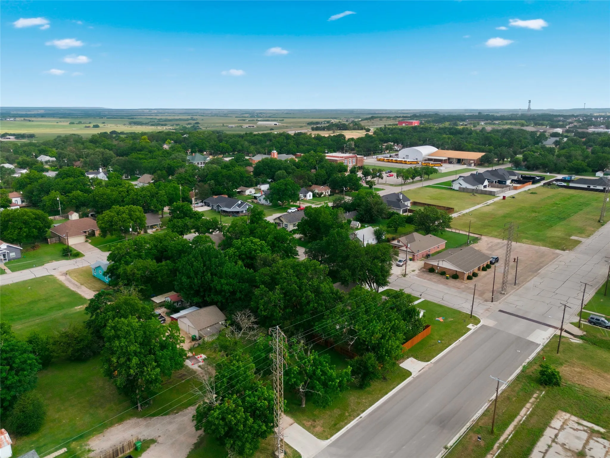 Aerial perspective showcasing a developed neighborhood with mature trees and a flat, clear land parcel