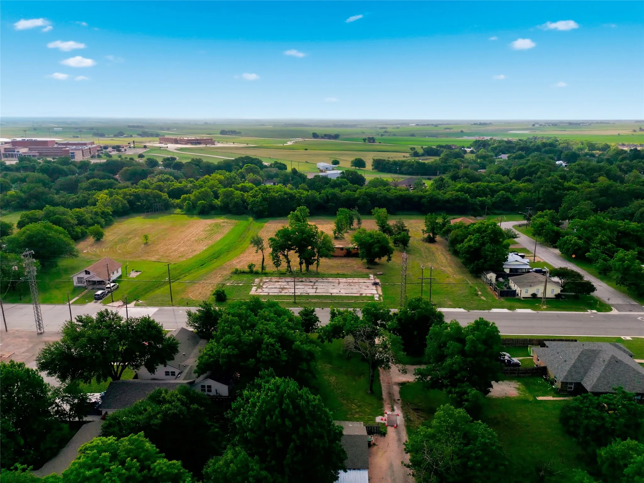 Expansive aerial overview revealing significant land parcels with surrounding residential and commercial structures