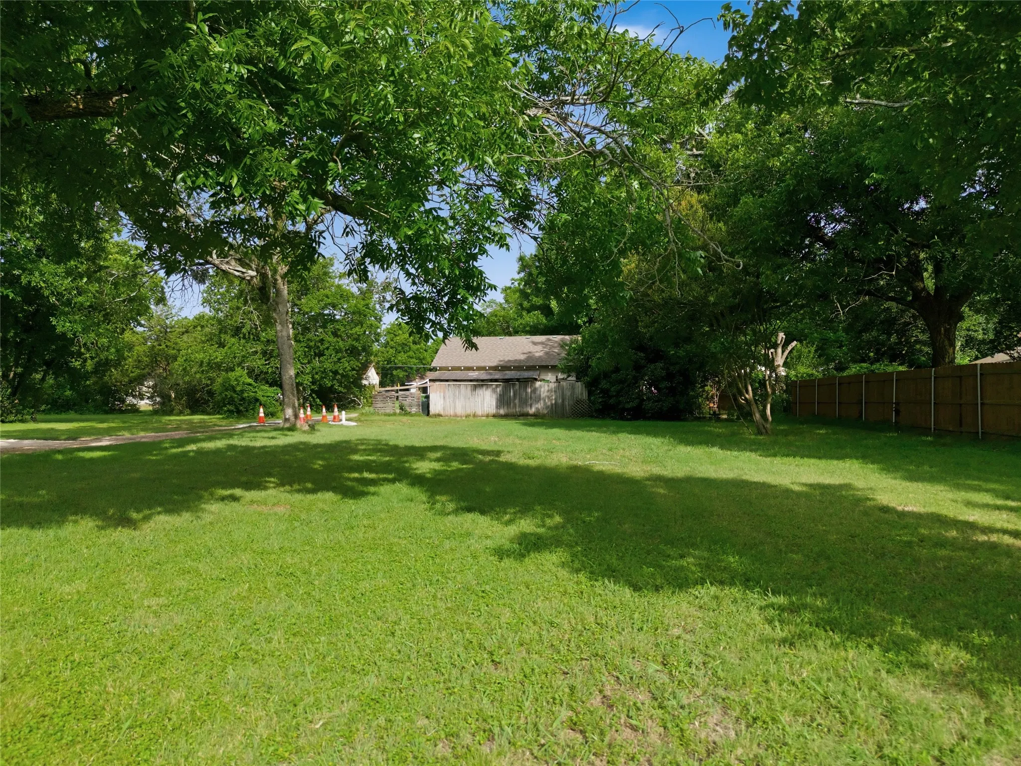 Expansive grassy lot featuring mature trees providing natural shade