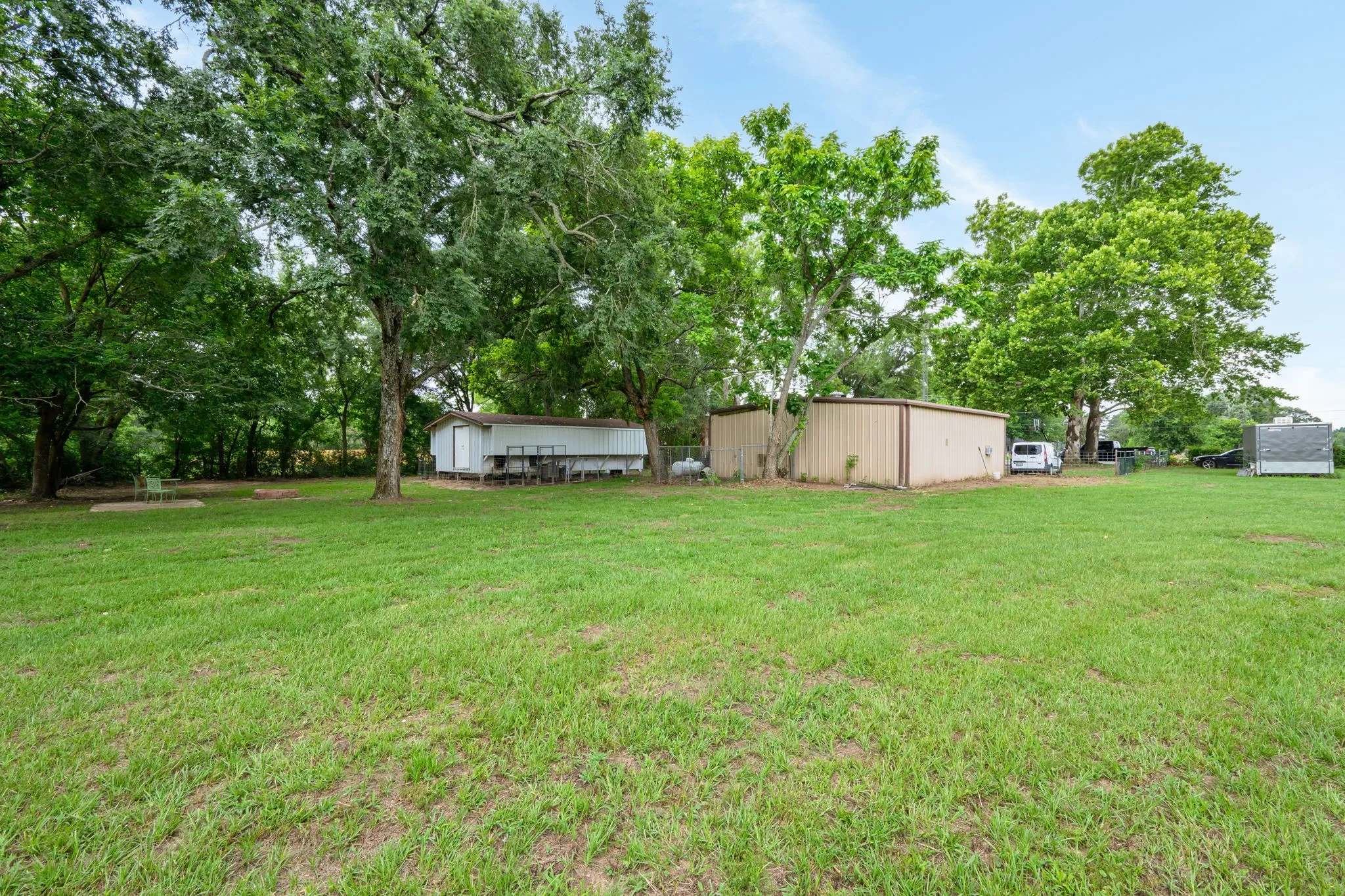 Expansive green lawn with mature trees providing shade