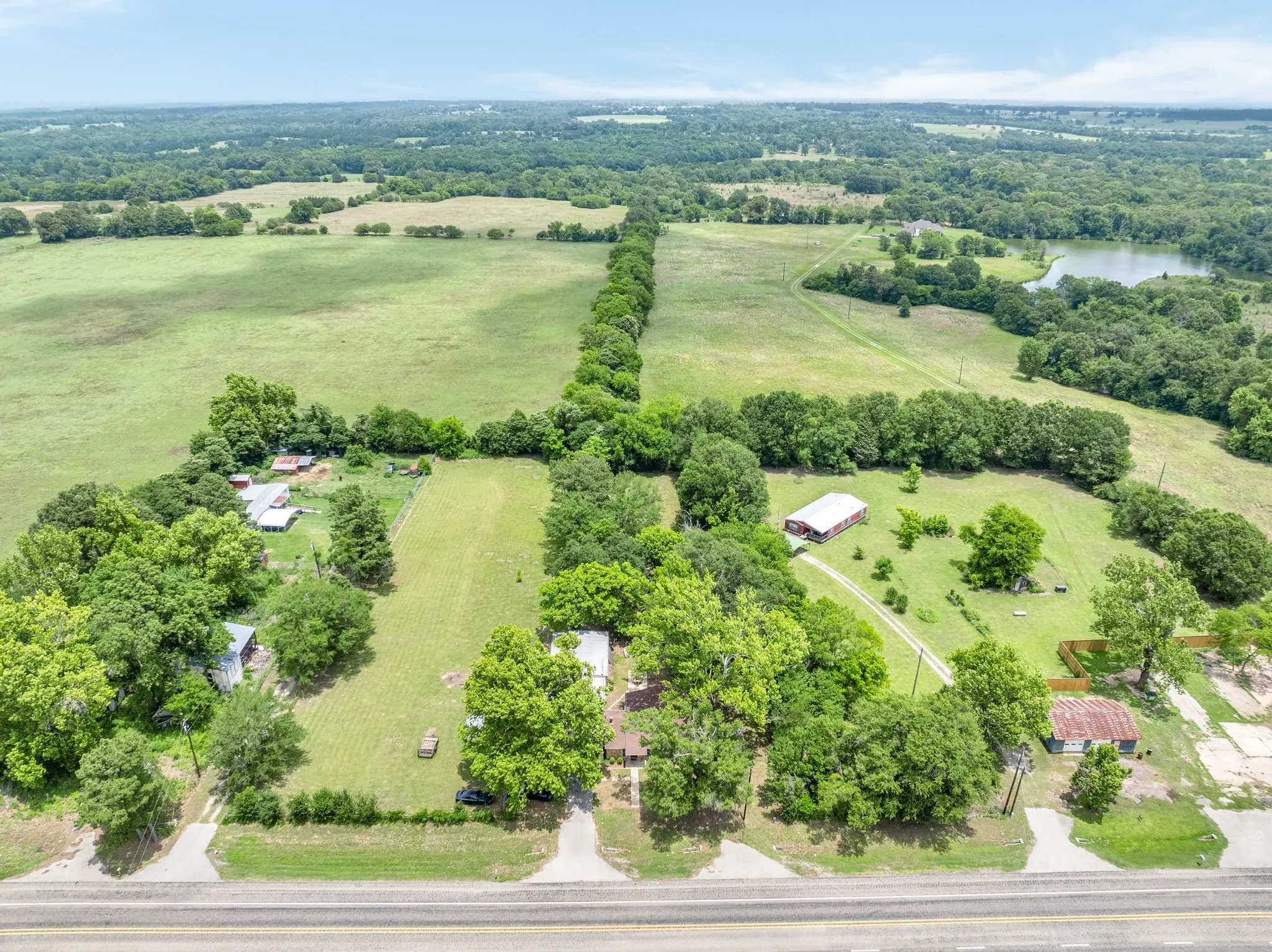 Expansive rural landscape featuring wooded areas, open fields, and a visible body of water