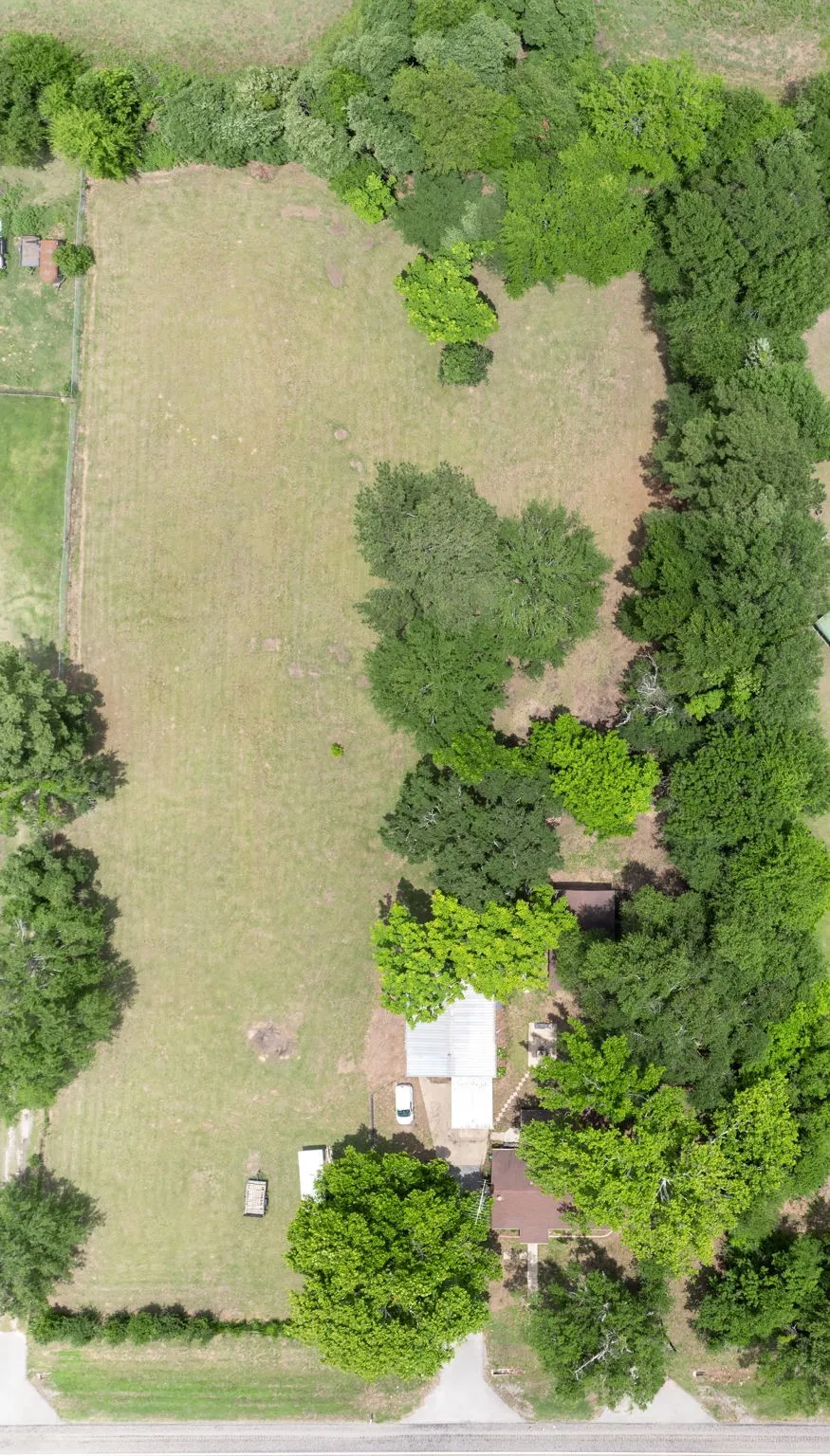 Expansive property featuring a mix of open grassy areas and mature tree coverage