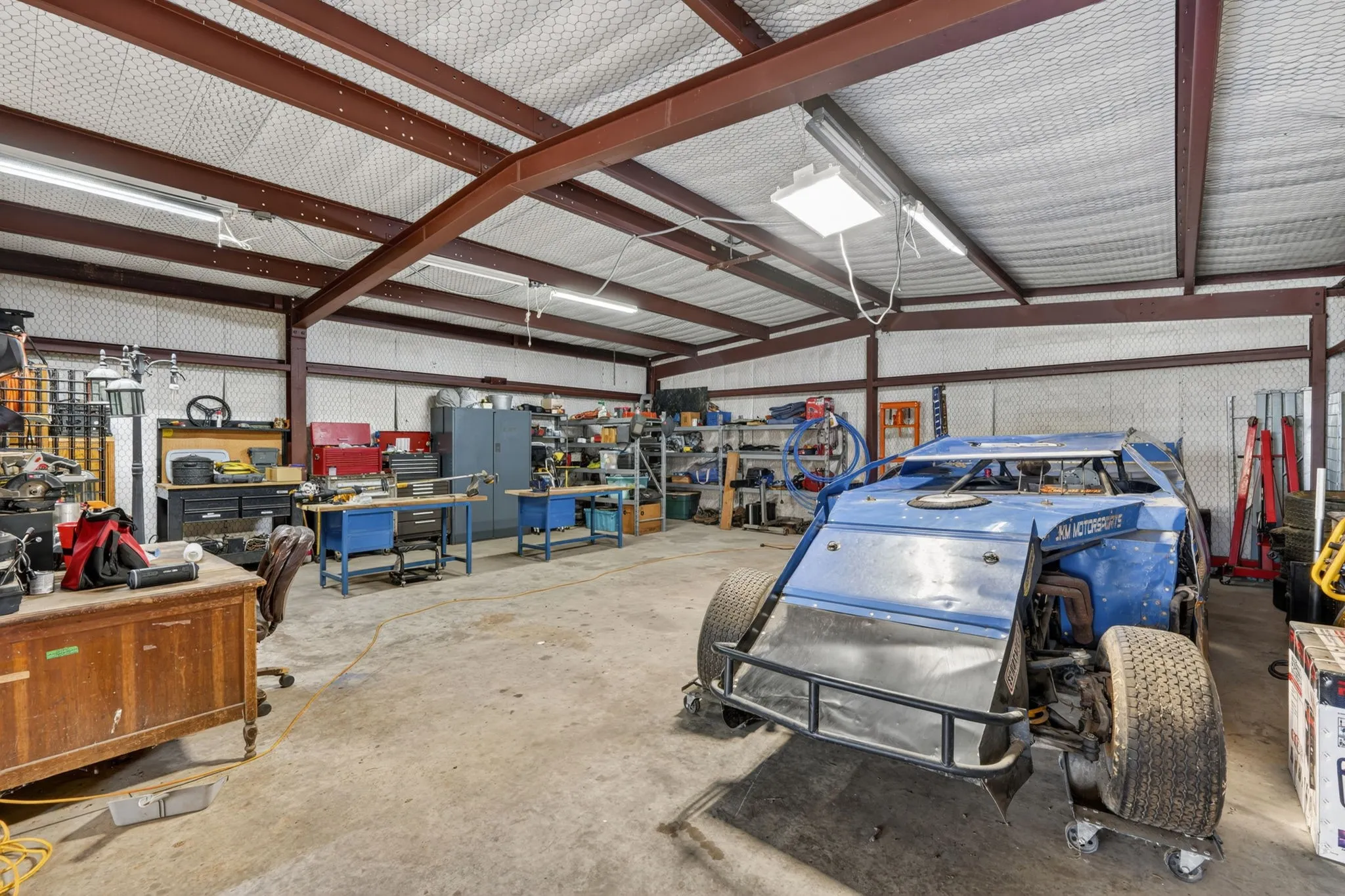 Spacious metal-frame building featuring a concrete floor, exposed steel beams, and overhead fluorescent lighting