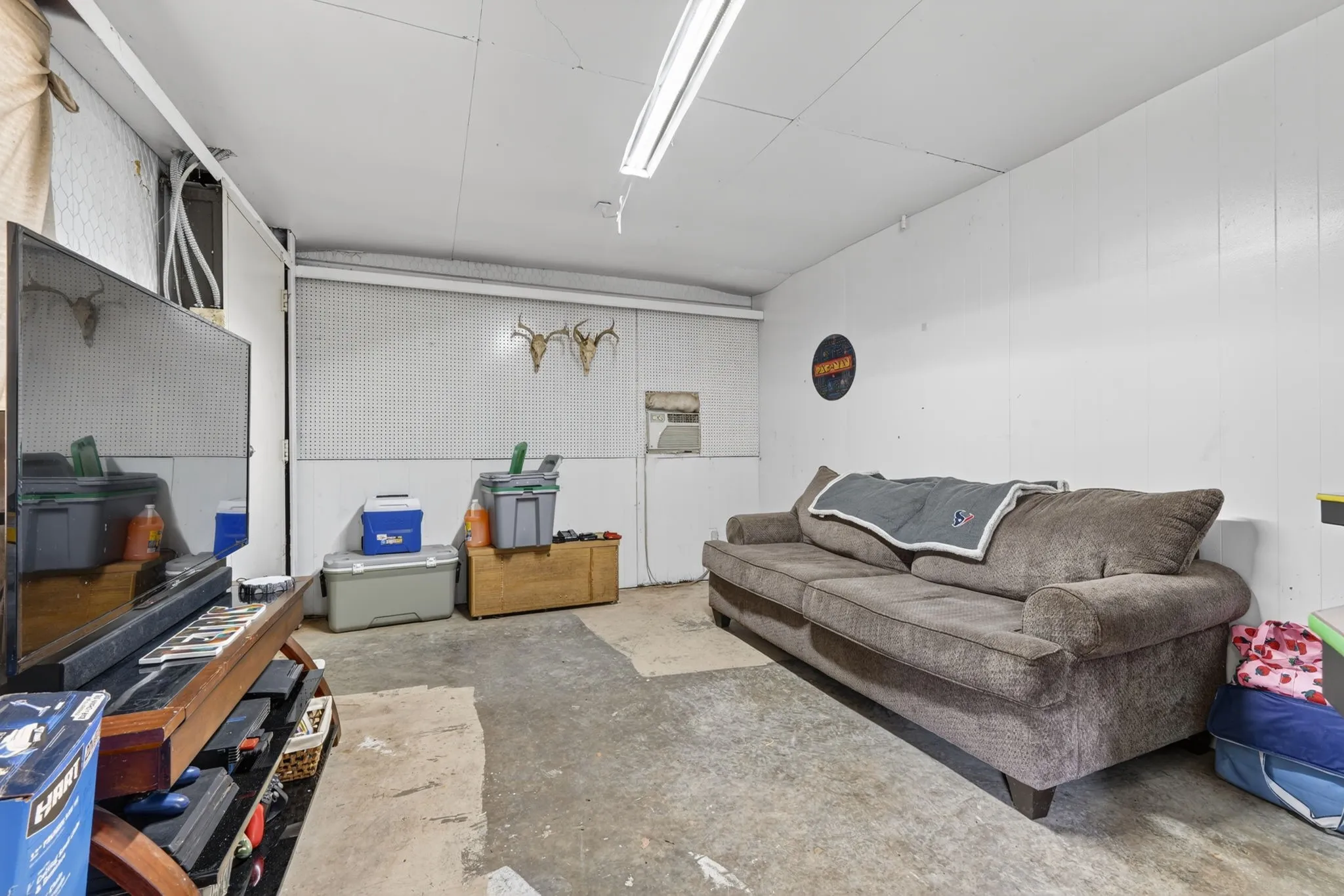 Utility room featuring white paneling, exposed ceiling joists, and concrete flooring