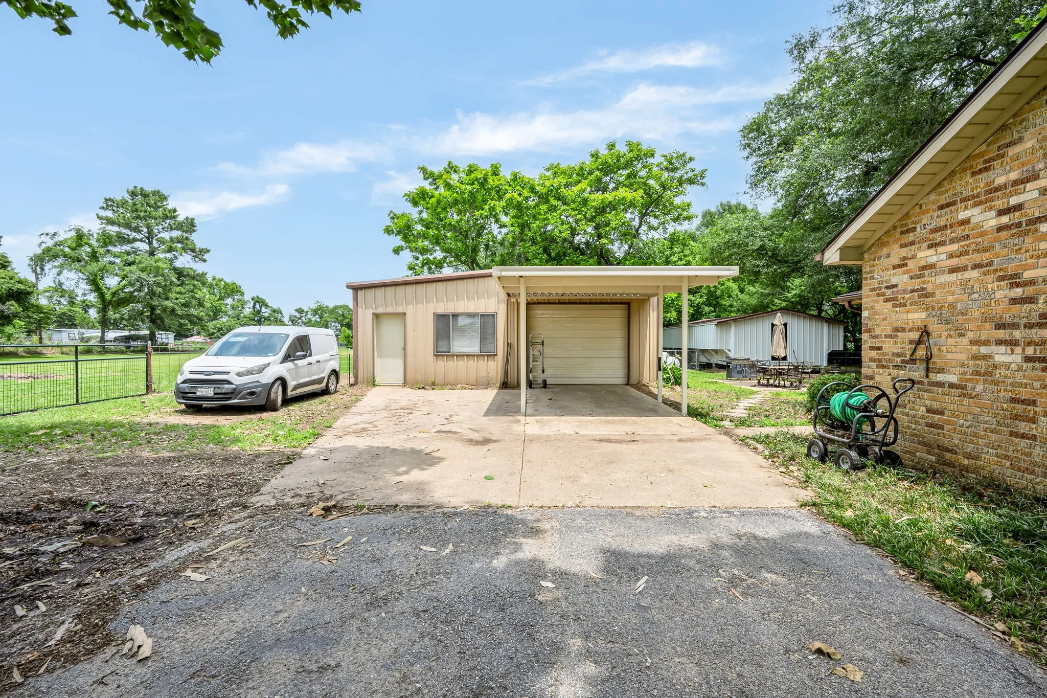 Detached garage with an overhead door, an attached carport, and a side access door, alongside a separate brick structure