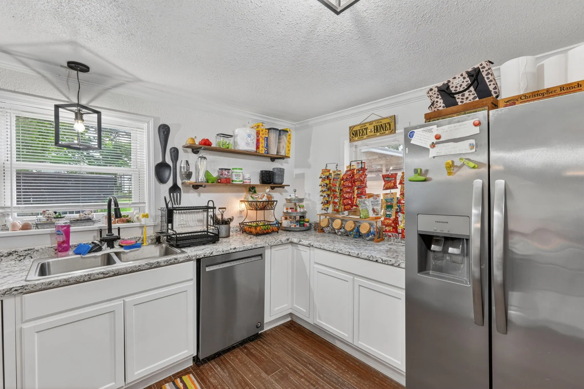Kitchen featuring white cabinetry, speckled countertops, stainless steel appliances, a double basin sink, and wood-finish flooring
