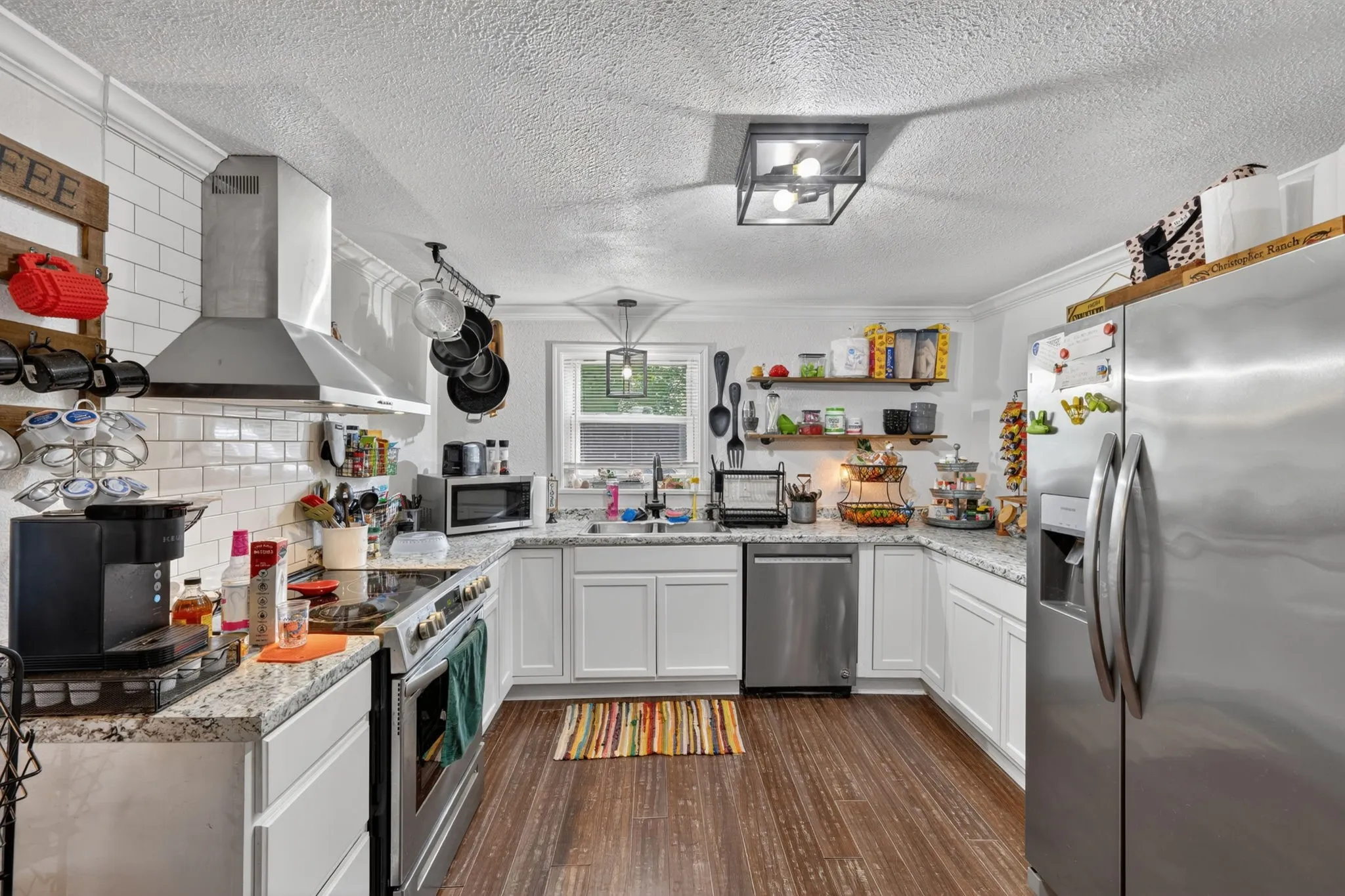 Kitchen featuring white shaker cabinetry, speckled countertops, and wood-finish flooring