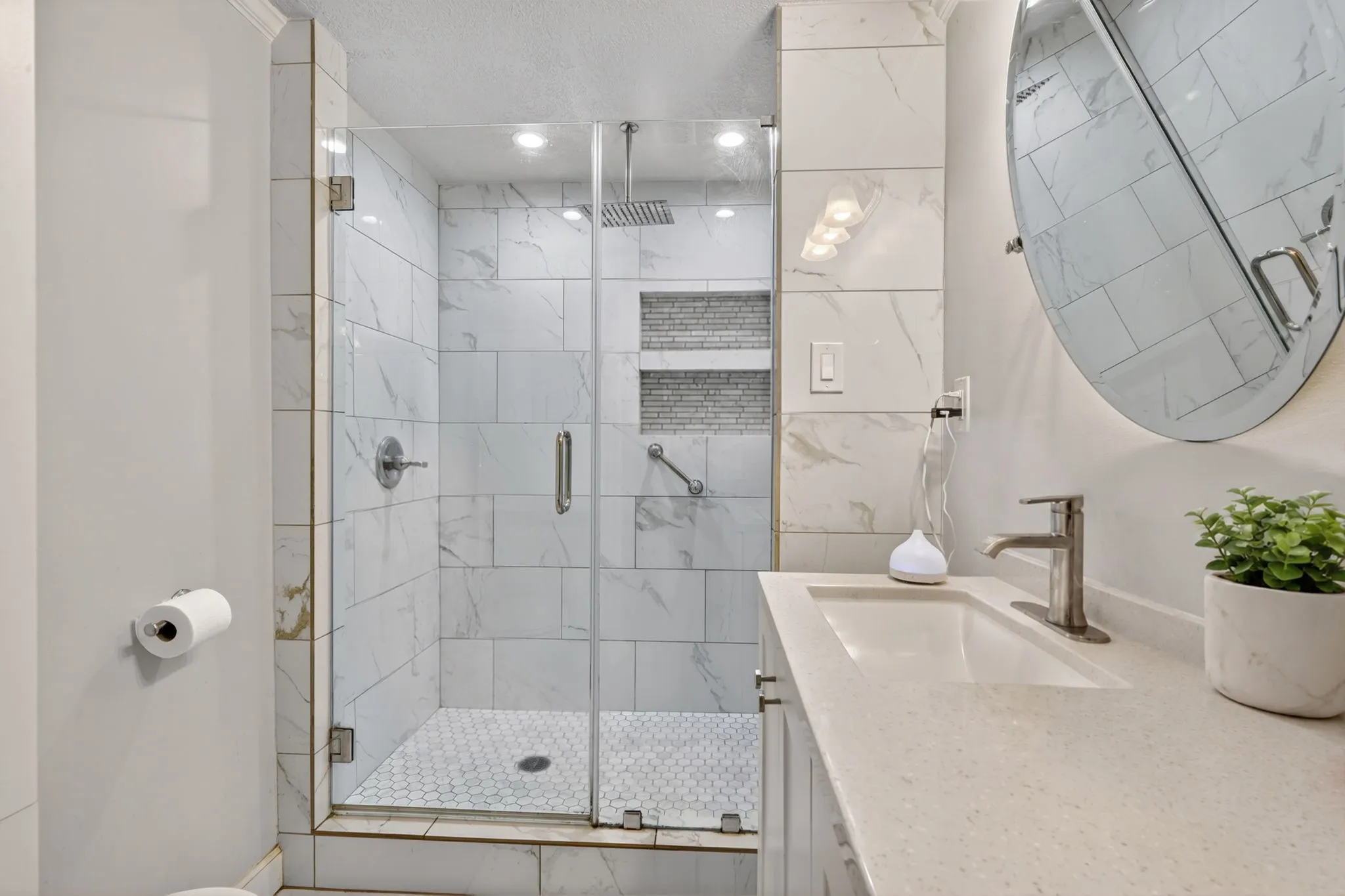 Glass-enclosed shower with subway-style wall tiling and hexagonal floor tiles