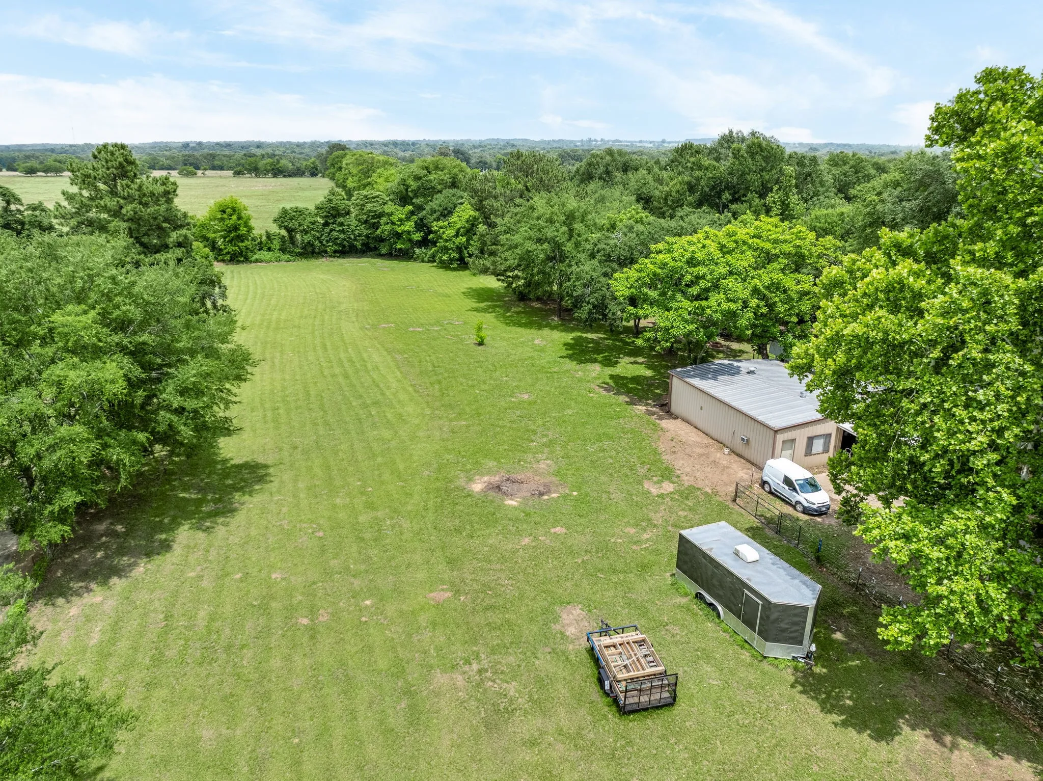 Expansive green acreage featuring mature trees and a distant tree line