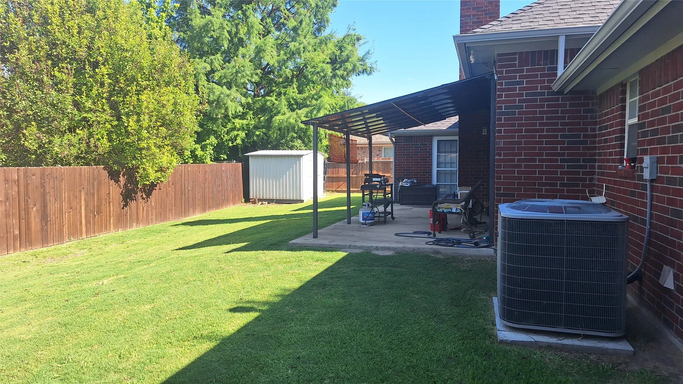 eastern backyard with metal roof covered porch within 21x10 patio. metal shed, 4 ton AC, updated stained privacy fence