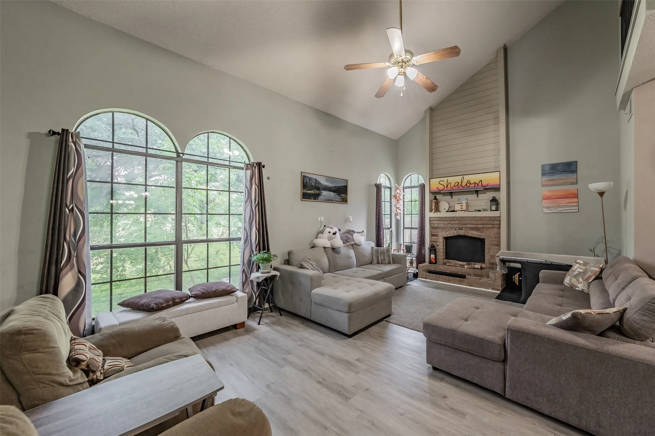 Living area featuring vaulted ceilings, wood-finish flooring, and a brick fireplace