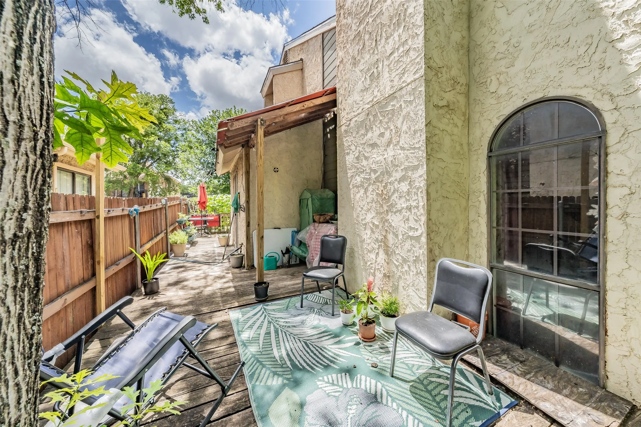 Private outdoor deck space featuring wood-finish flooring, a wood privacy fence, and an arched window with grid detailing
