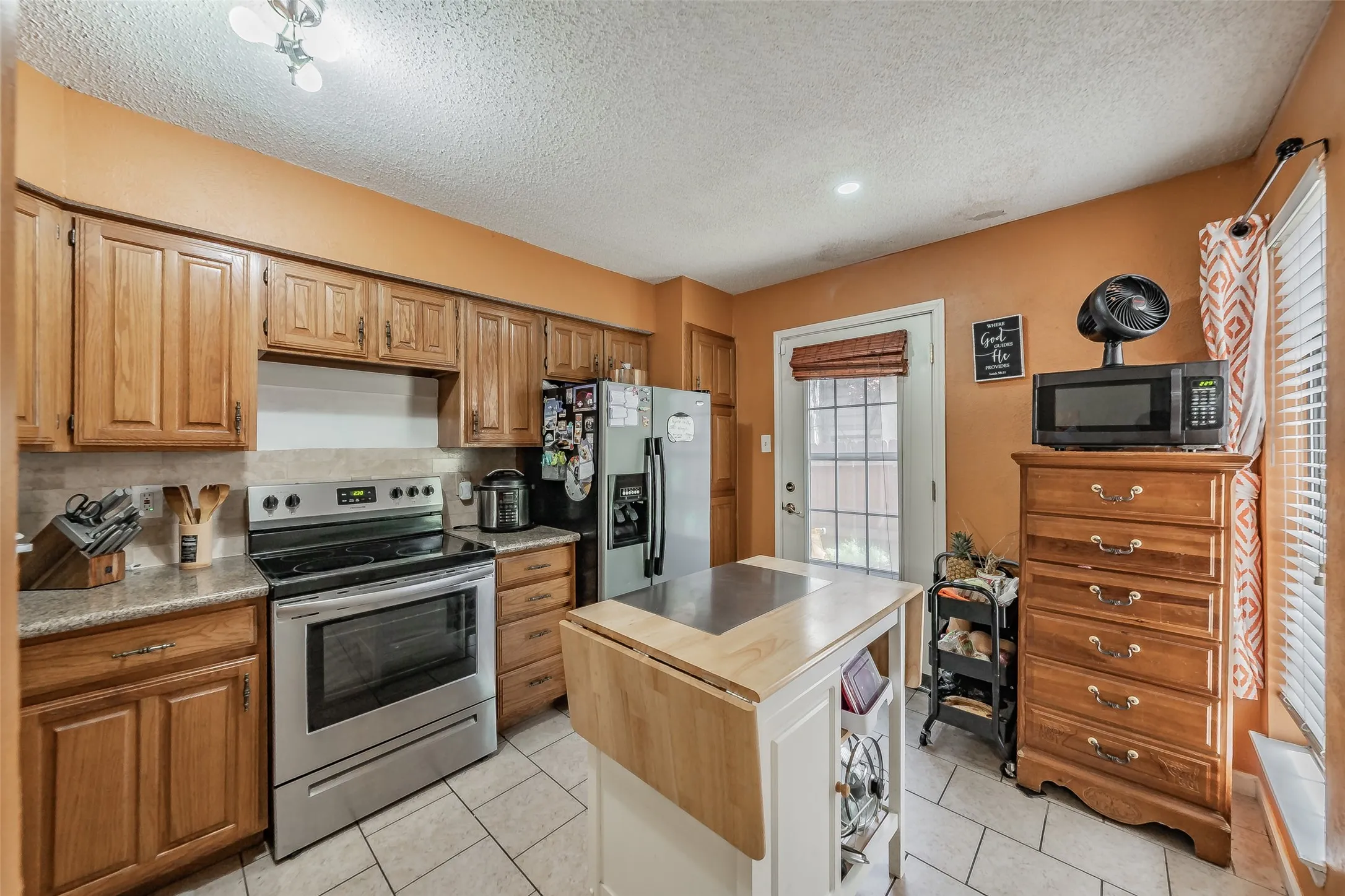 Kitchen featuring wood cabinetry, stainless steel range, and tile flooring