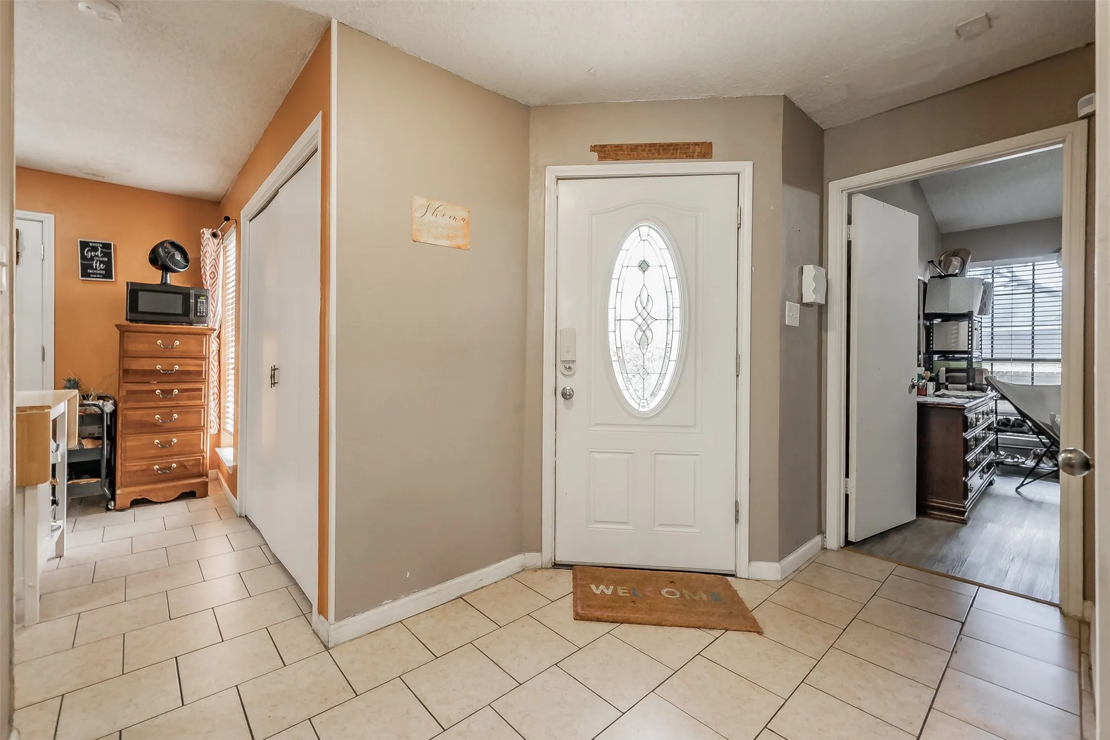 Entryway featuring neutral wall tones, ceramic tile flooring, and a white front door with an oval decorative glass insert