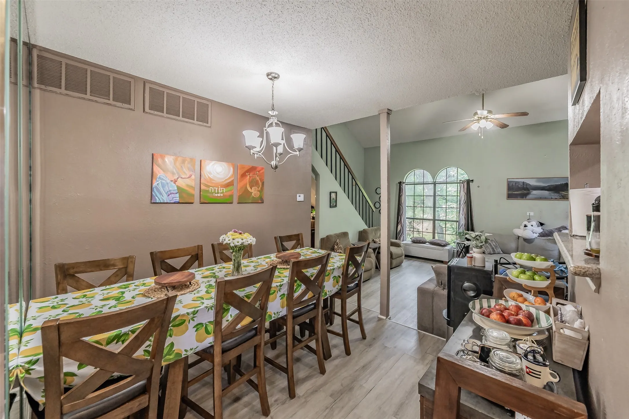 Spacious dining area with wood-finish flooring, a multi-light chandelier, and an integrated air return system