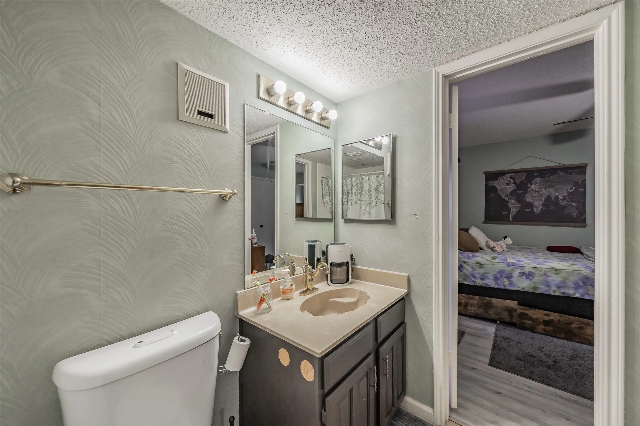Bathroom featuring a single vanity with an integrated sink, a wall-mounted mirror, and overhead lighting