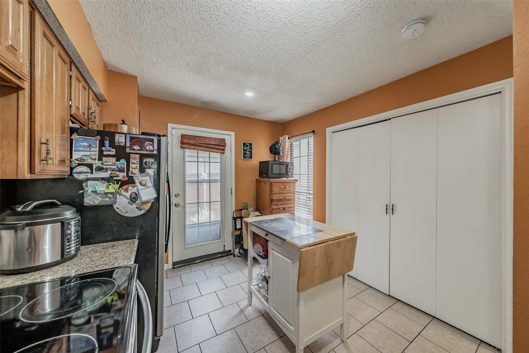 Kitchen featuring wood cabinetry, granite-look countertops, and tile flooring