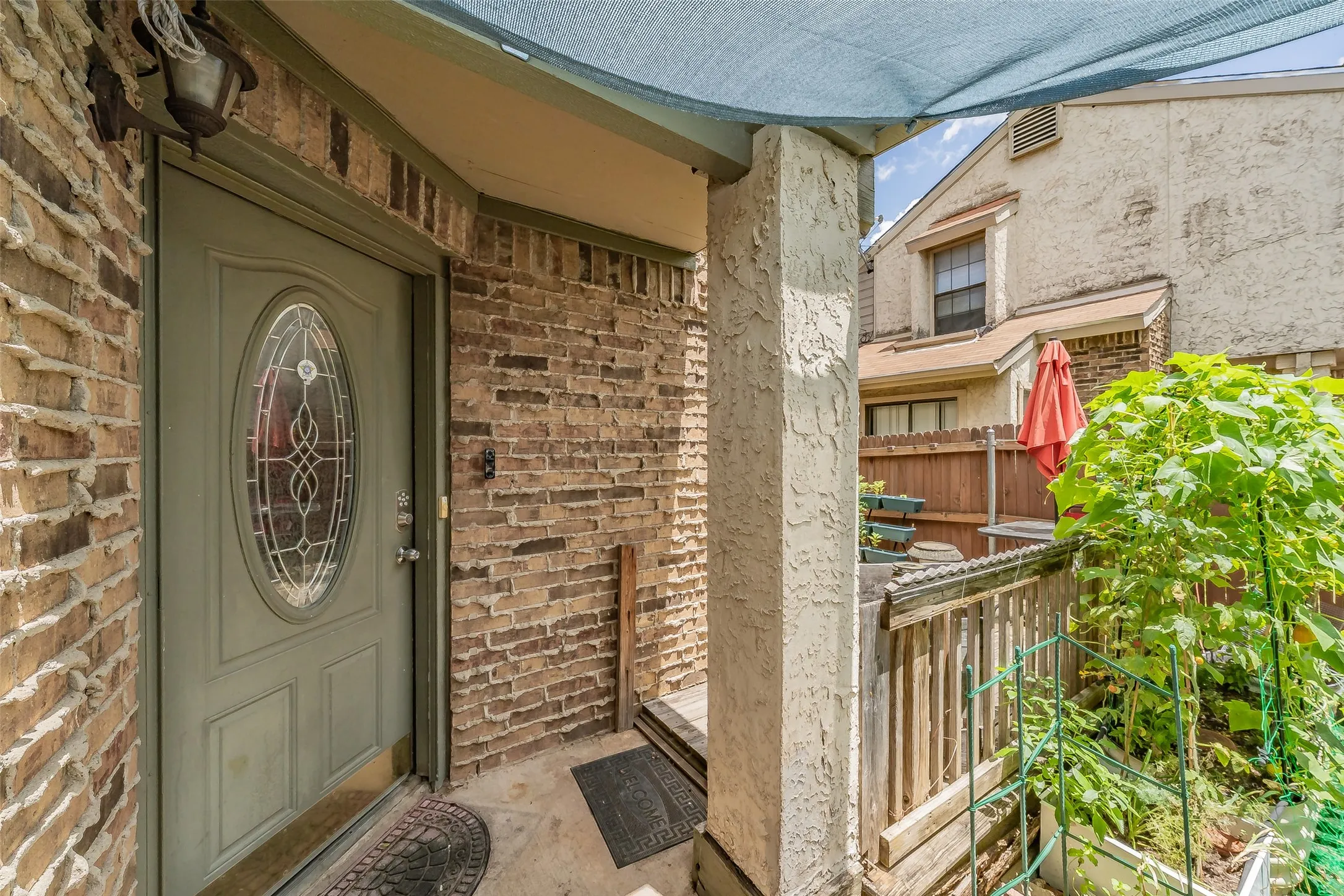 Brick exterior with a covered entryway, decorative glass panel door, and an exterior light fixture