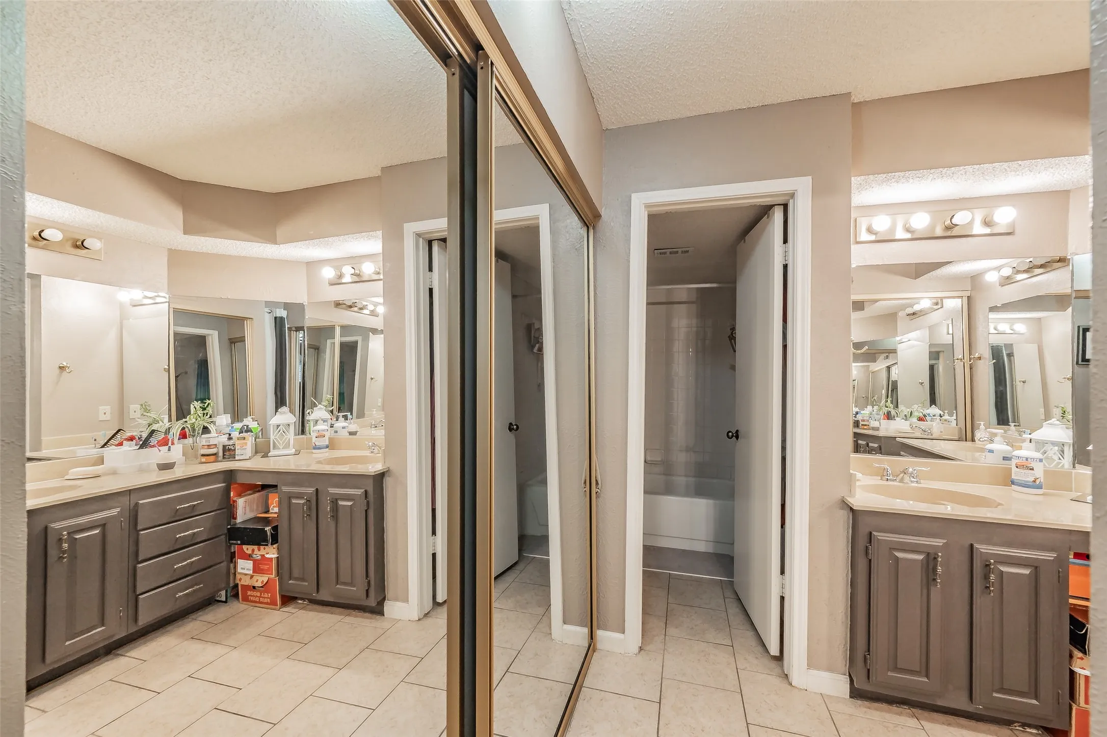 Bathroom featuring dual vanities, each with a single basin, ample countertop space, and task lighting