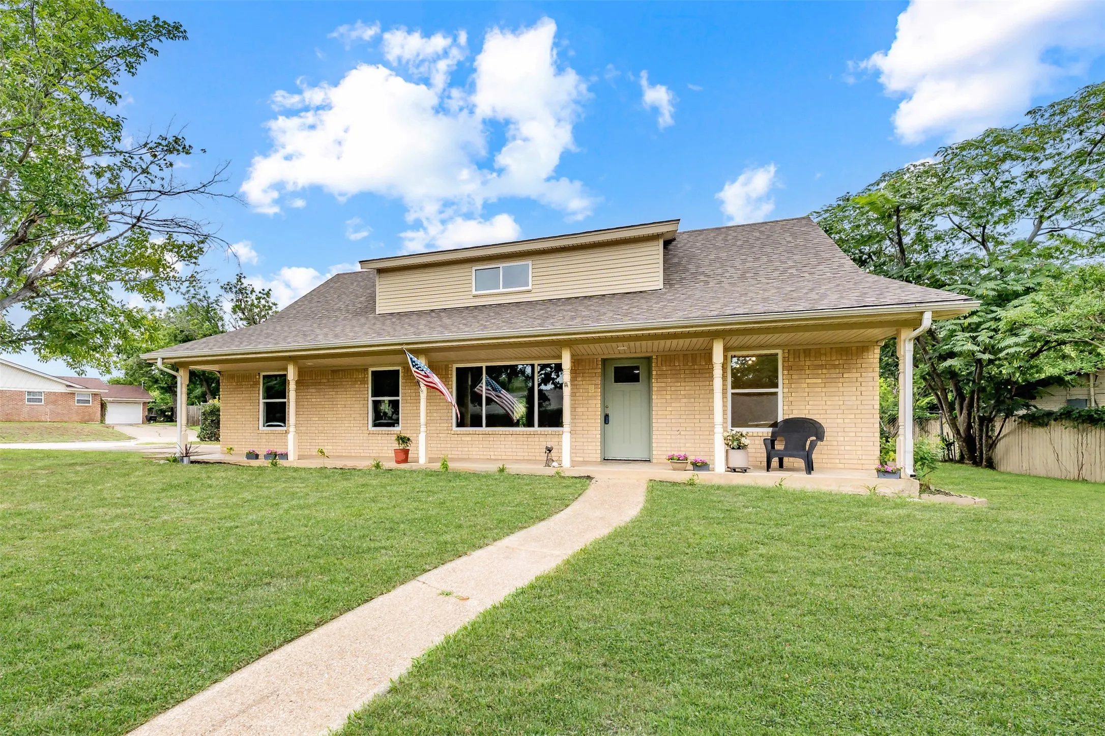 Ranch-style residence featuring a brick facade, covered front porch, and a dormer window