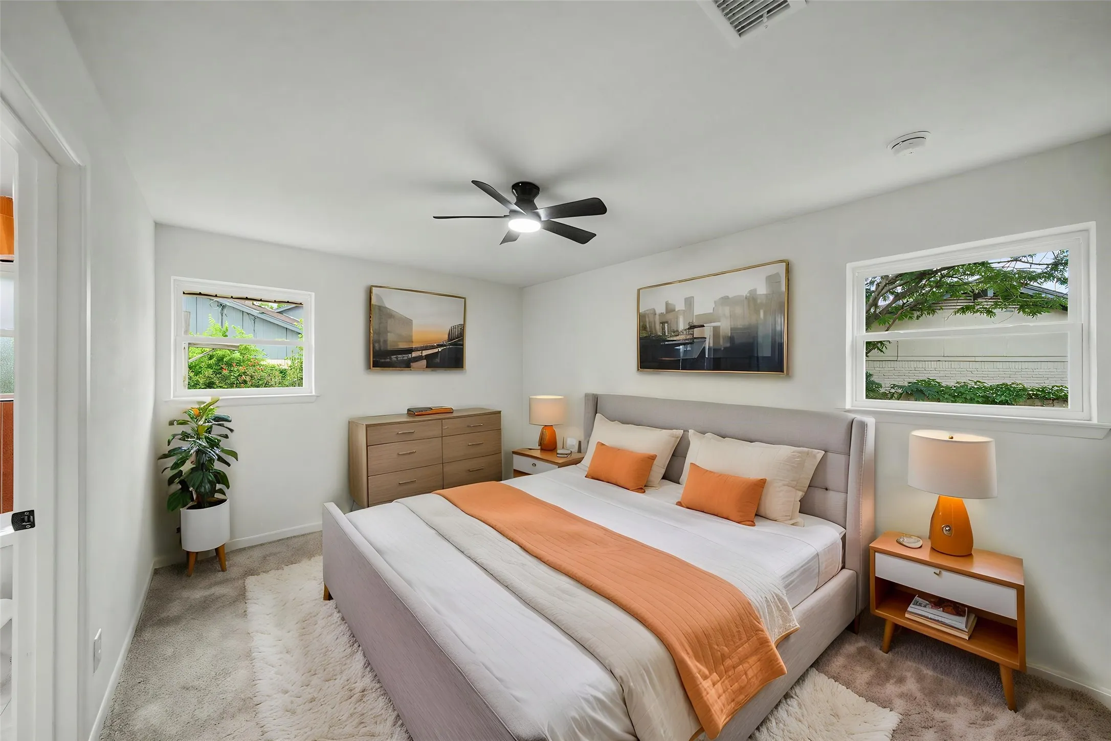 Carpeted bedroom featuring a ceiling fan, dual windows, and light-toned walls