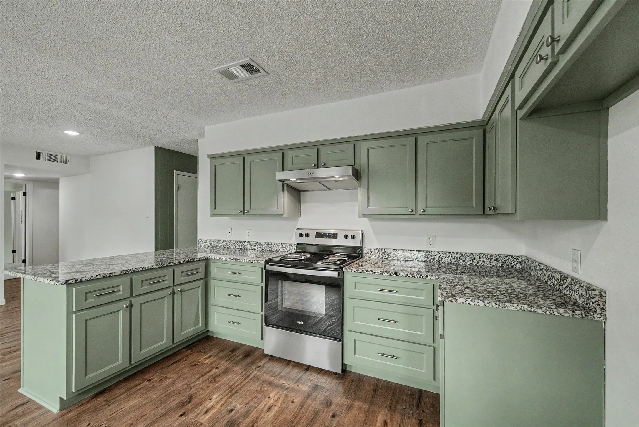 Kitchen featuring L-shaped granite countertops with a matching backsplash