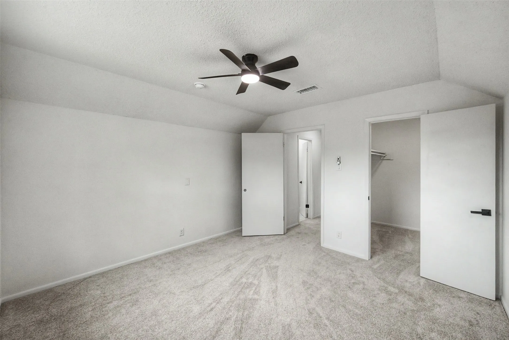 Carpeted room featuring a ceiling fan with integrated lighting, a white painted interior, a closet with wire shelving, and modern black door hardware