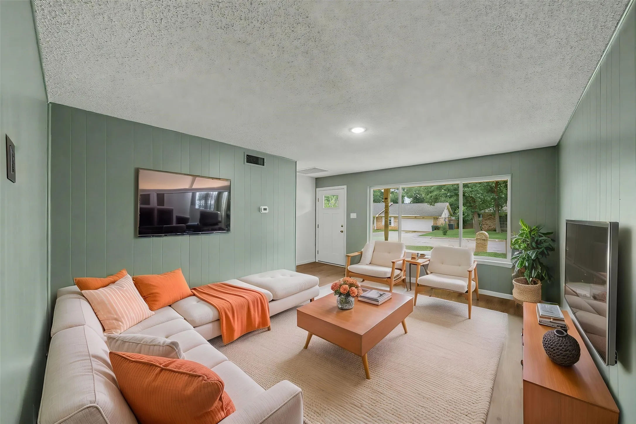 Spacious living area featuring paneling walls, recessed lighting, and wood-finish flooring