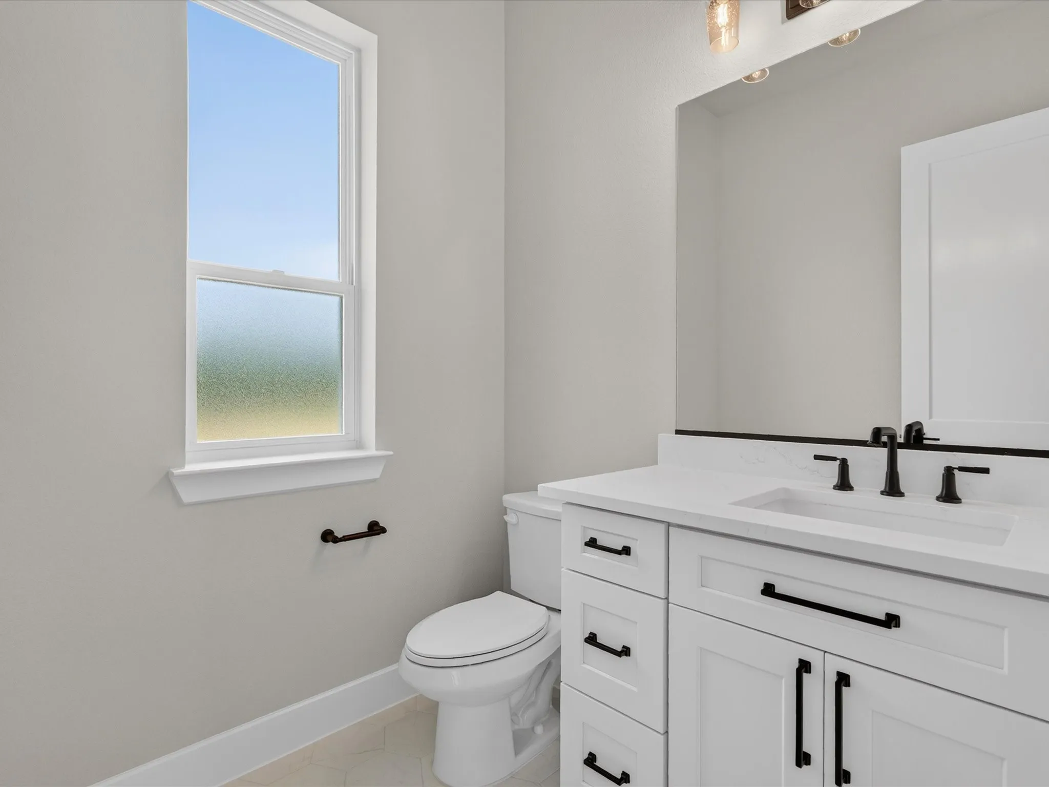 White shaker-style vanity with matte black hardware, integrated rectangular sink, and white countertop