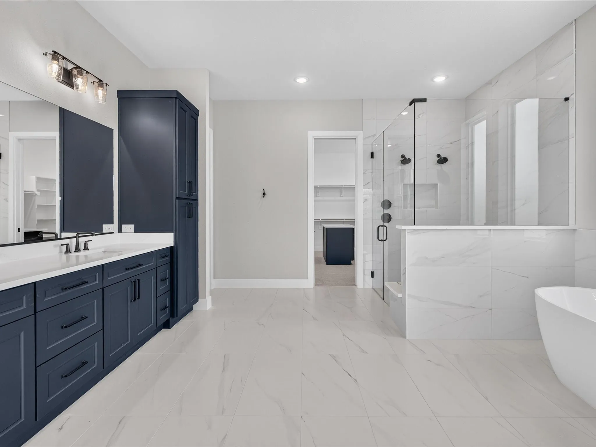 Spacious bathroom featuring a double vanity with dark cabinetry, integrated rectangular sinks, and a large mirror
