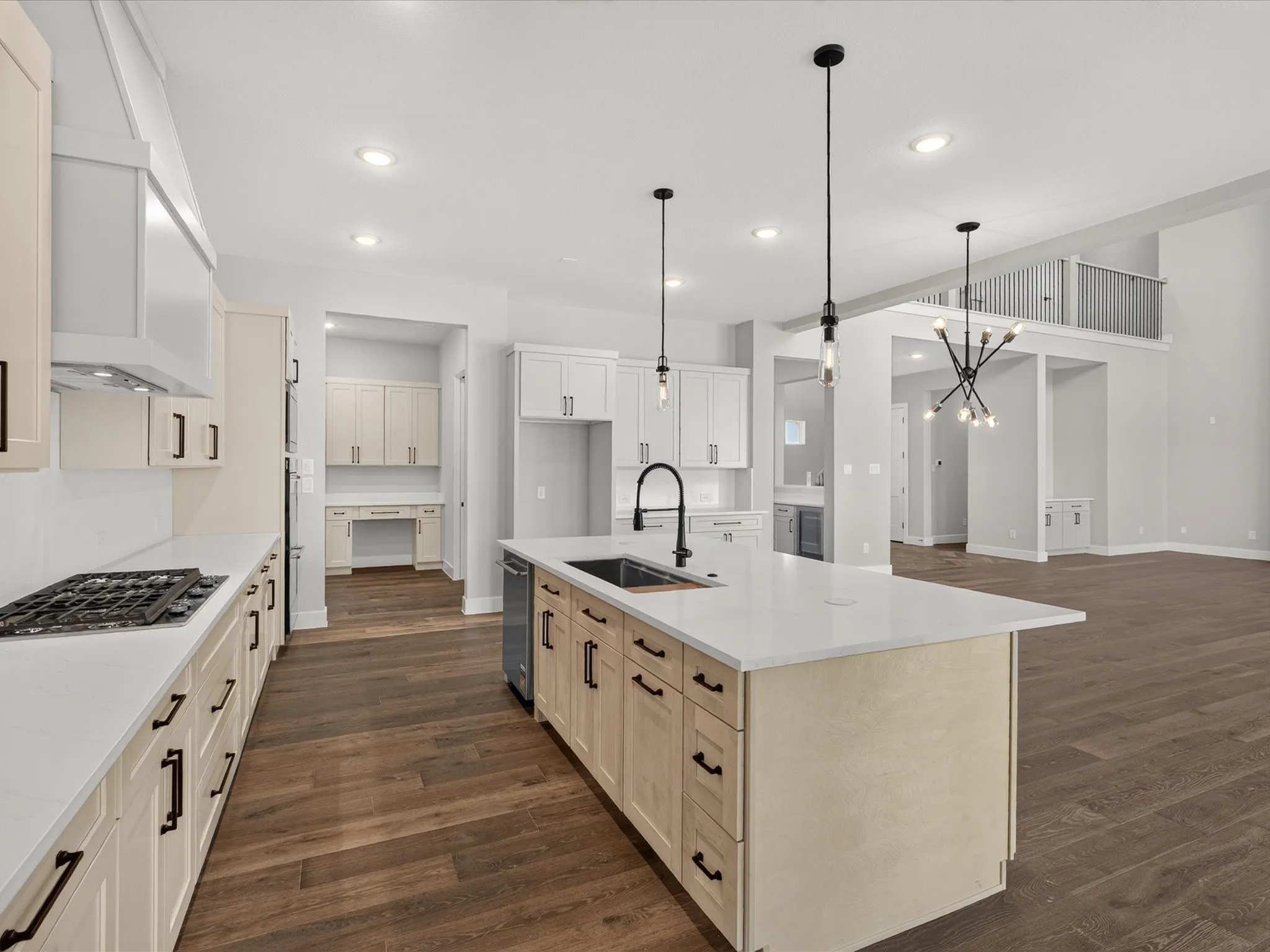 Expansive kitchen featuring a center island with sink, white countertops, built-in gas range, wood-finish flooring, and pendant lighting