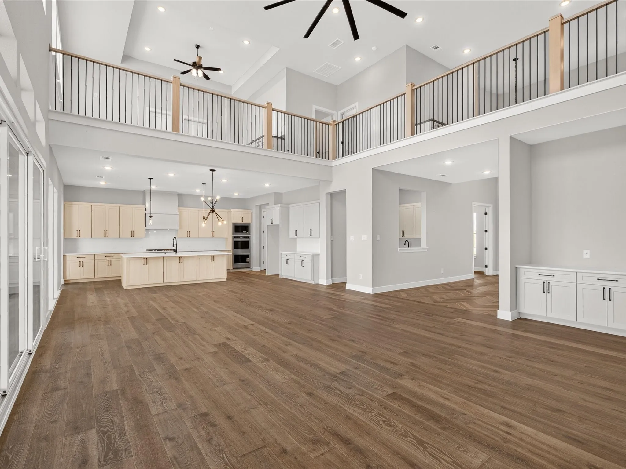 Open-concept living area with wood-finish flooring, a two-story ceiling, and an upper-level railing