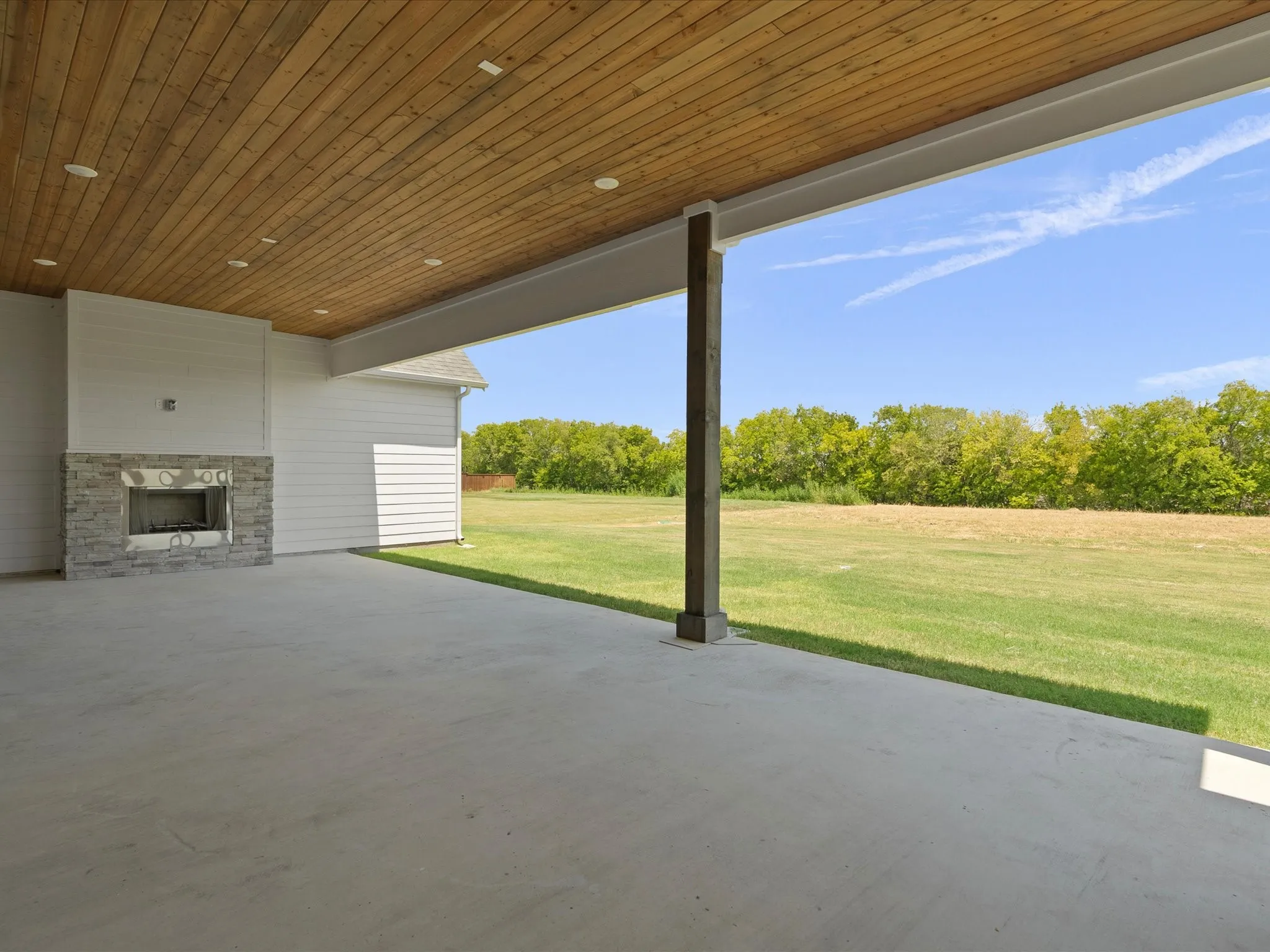 Covered patio with a wood-finish ceiling, recessed lighting, and a stone-clad outdoor fireplace