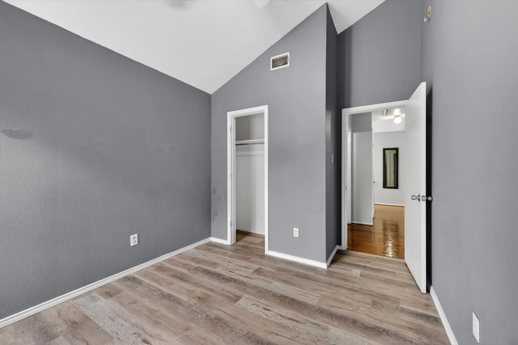 Room featuring wood-finish flooring, vaulted ceilings, and a neutral wall color
