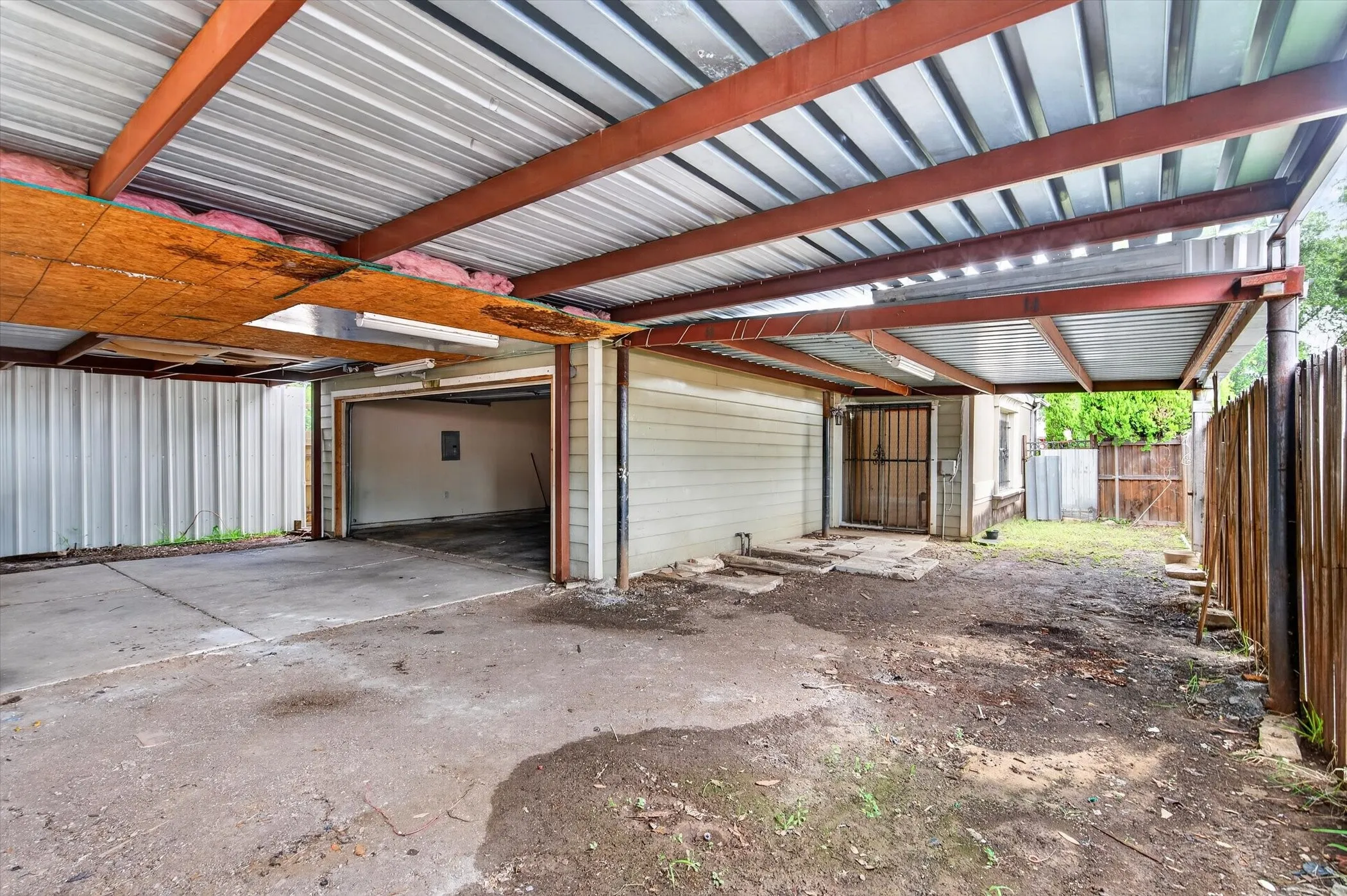 Covered carport structure with an open garage bay and an additional enclosed storage area